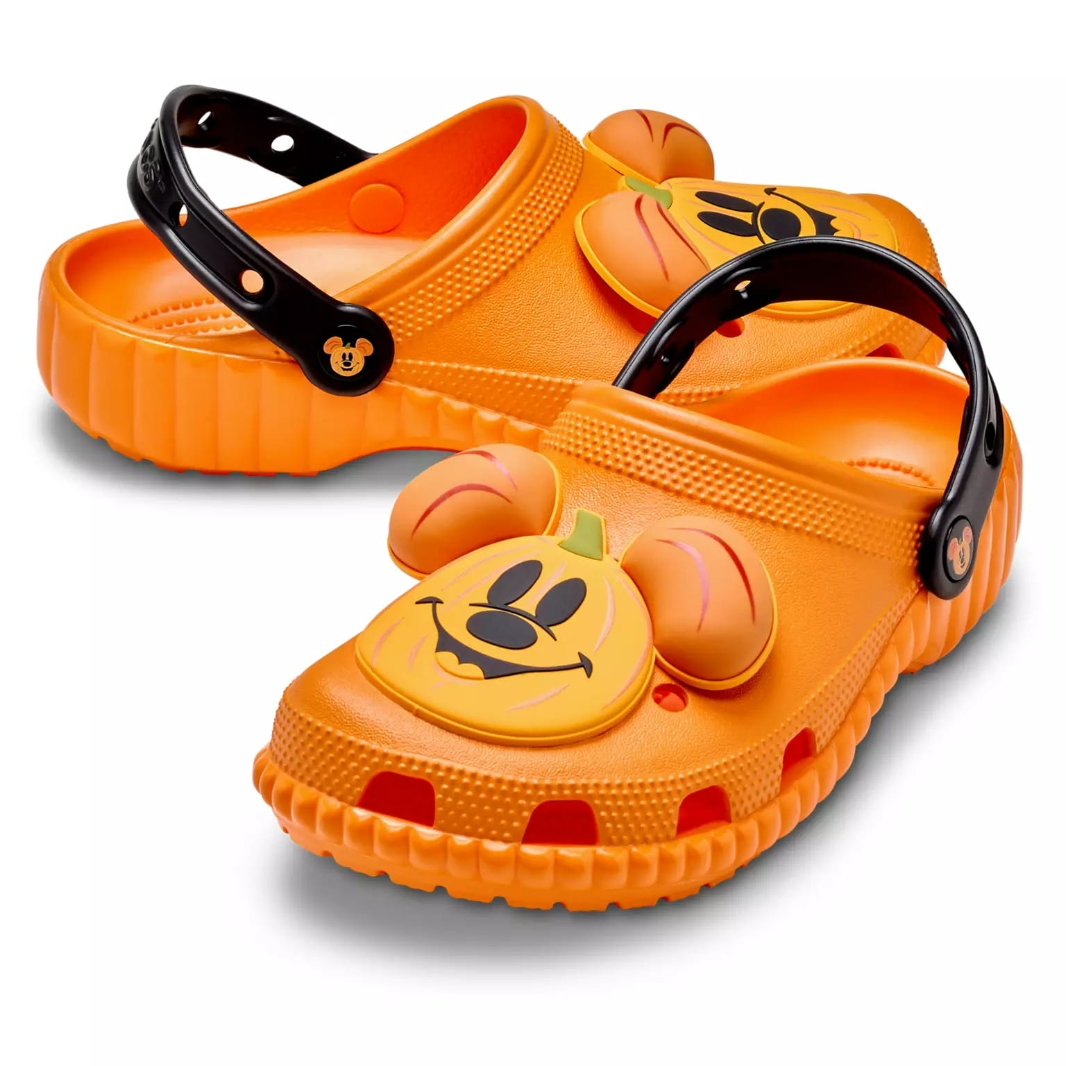 Orange Crocs with black straps and a 3D pumpkin Mickey face, part of the Disney Store Halloween merchandise collection.