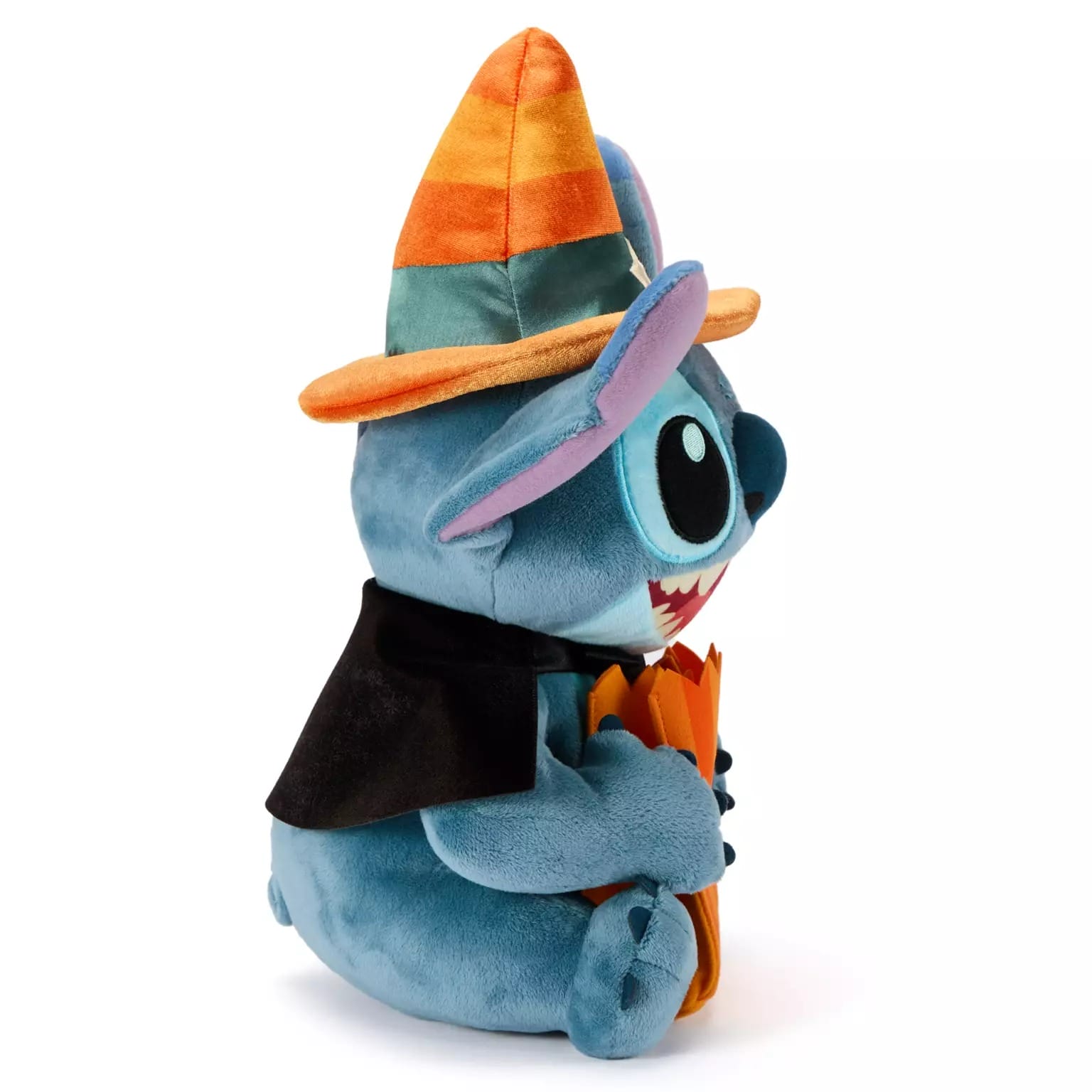 Plush toy of Stitch in a witch hat and cape, holding an orange item—perfect Disney Store Halloween merchandise.