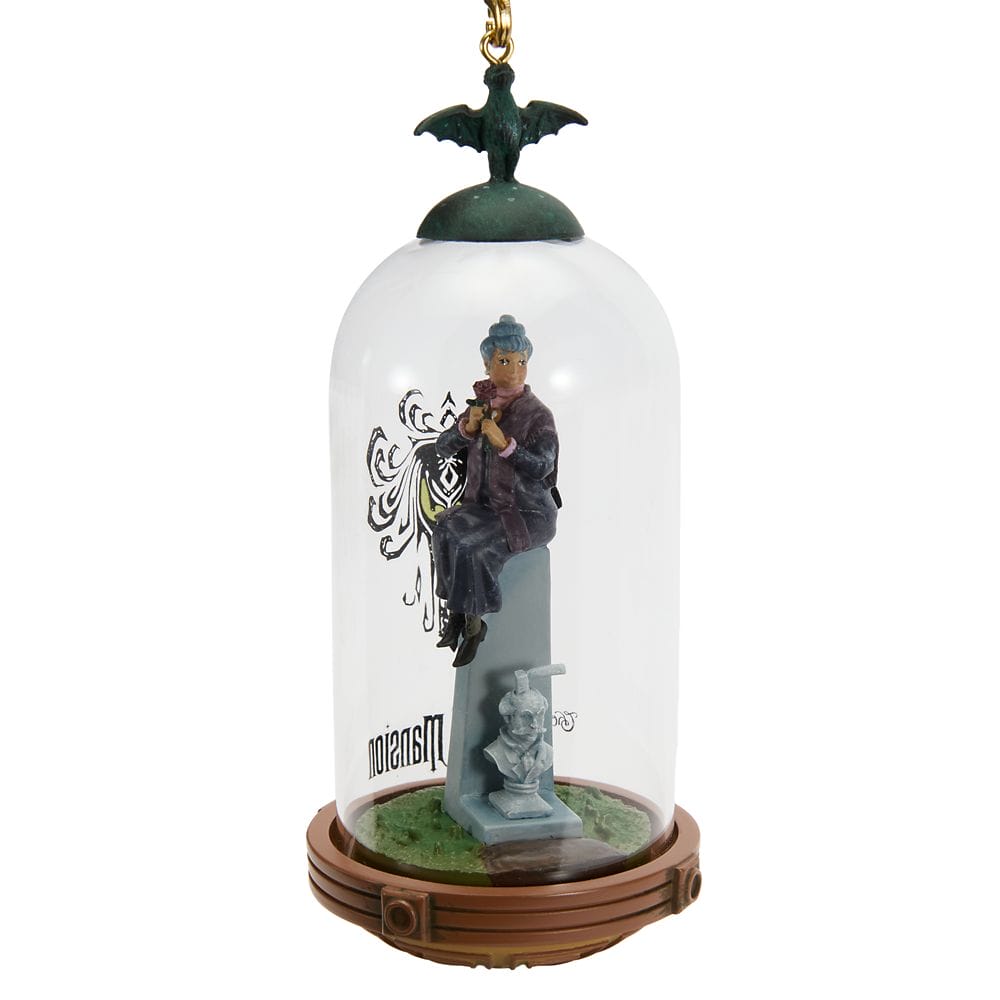 A figurine of a man on a tombstone in a glass dome with a bat, part of the Disney Store Haunted Mansion Collection.