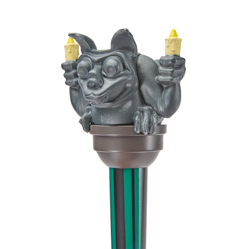A gray gargoyle candleholder from the Haunted Mansion Collection sits atop a green and black striped pole.