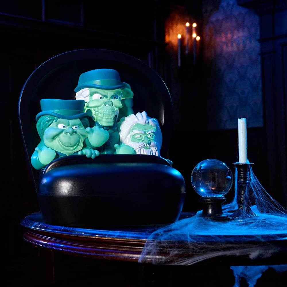 Three ghostly figurines in a black buggy evoke the Haunted Mansion on a cobweb-covered table with a crystal ball.