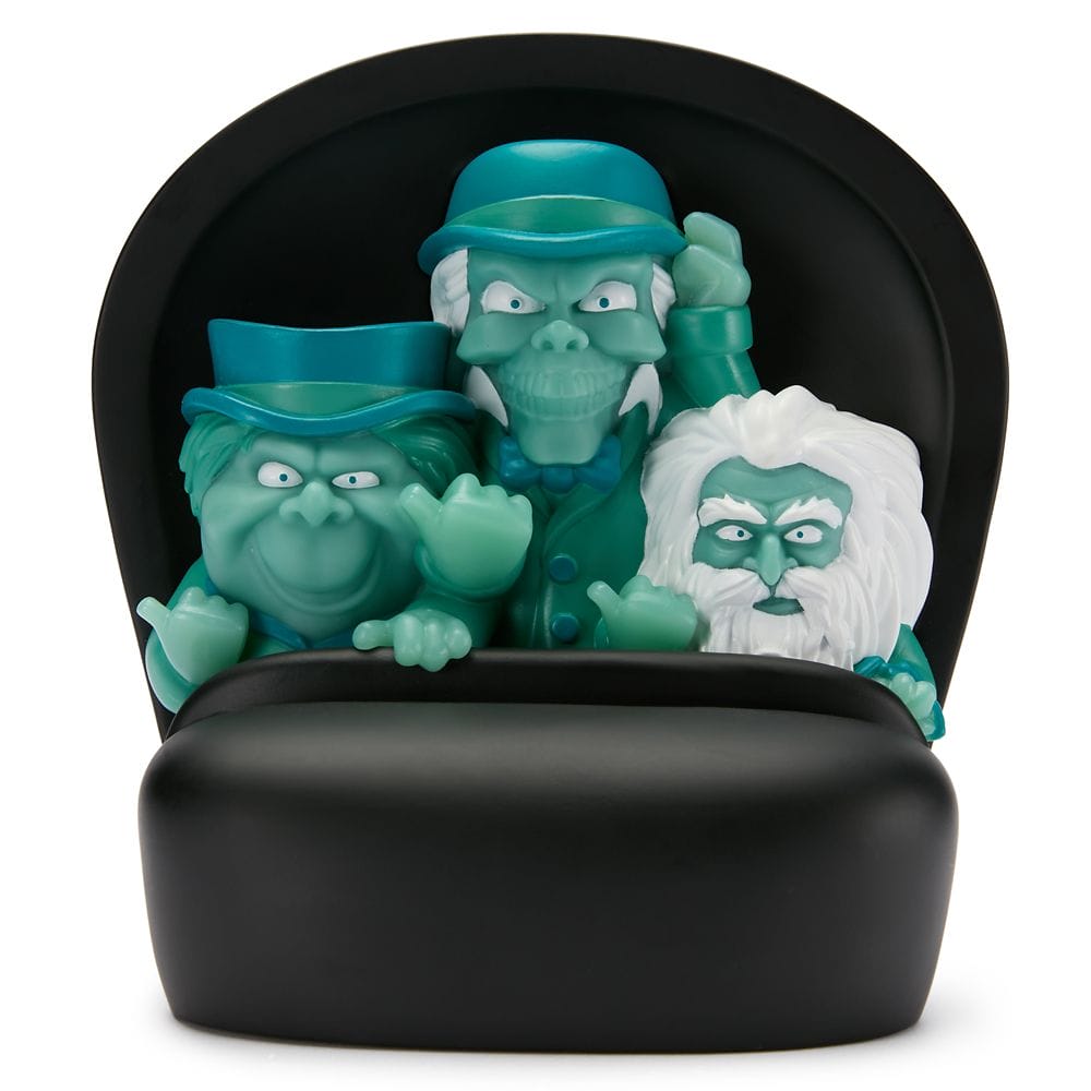 Three ghostly cartoon figures with blue-green skin ride a black doom buggy from the Haunted Mansion.