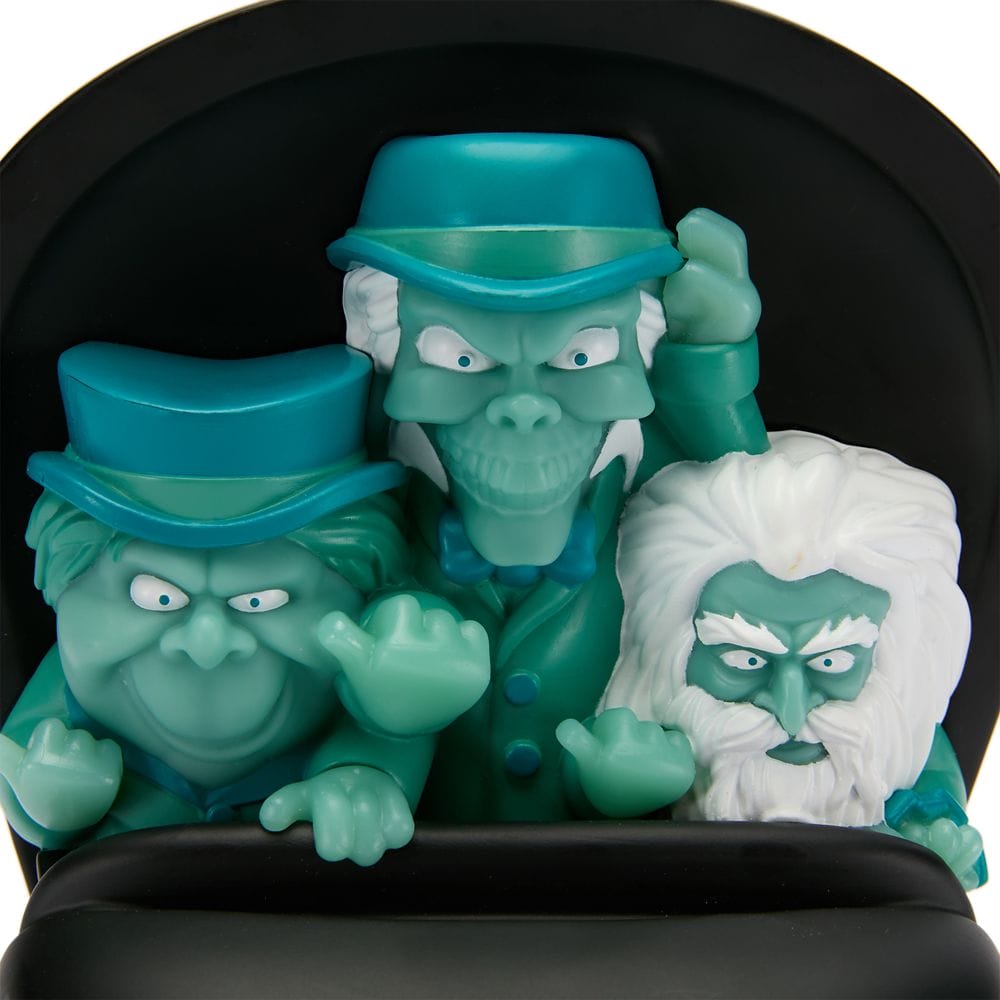 Three ghostly, blue-green figures from the Haunted Mansion sit in a ride vehicle, part of the Haunted Mansion Collection.