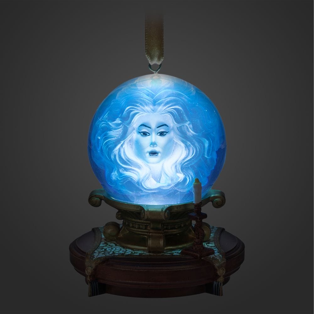 A glowing blue crystal ball with a ghostly woman's face, from the Haunted Mansion Collection, rests on an ornate stand.