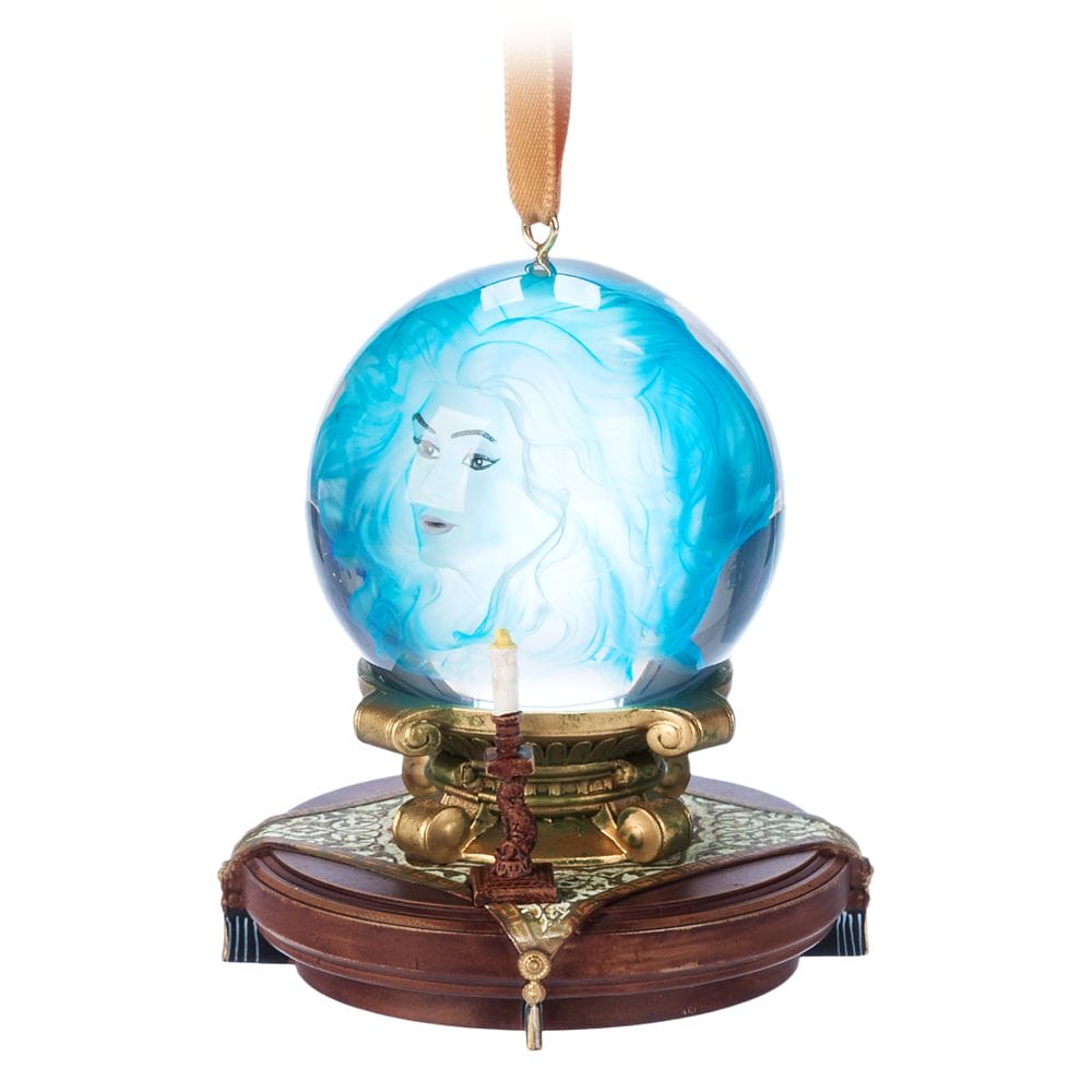 A crystal ball ornament from the Haunted Mansion Collection, set on an ornate base with a candle in front.