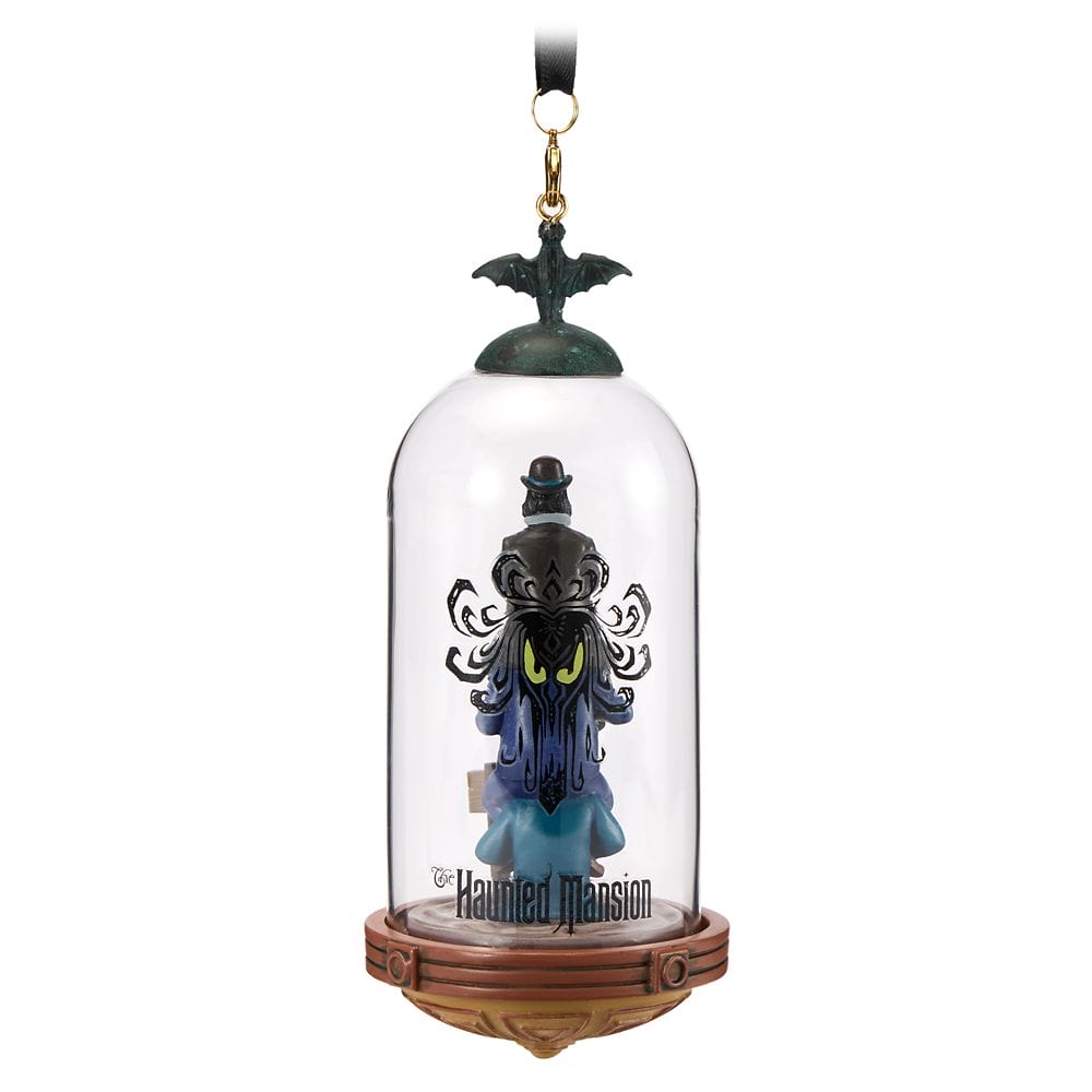 A Disney Store Haunted Mansion ornament features a ghostly figure in a glass dome with a bat and ribbon.