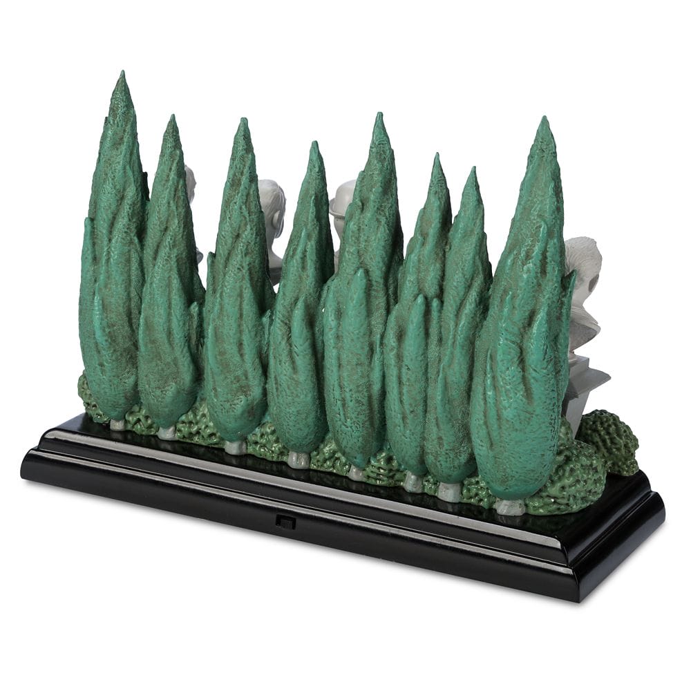 A row of tall, green cypress trees on a black base hints at Haunted Mansion figures hidden behind, inspired by Disney Store magic.