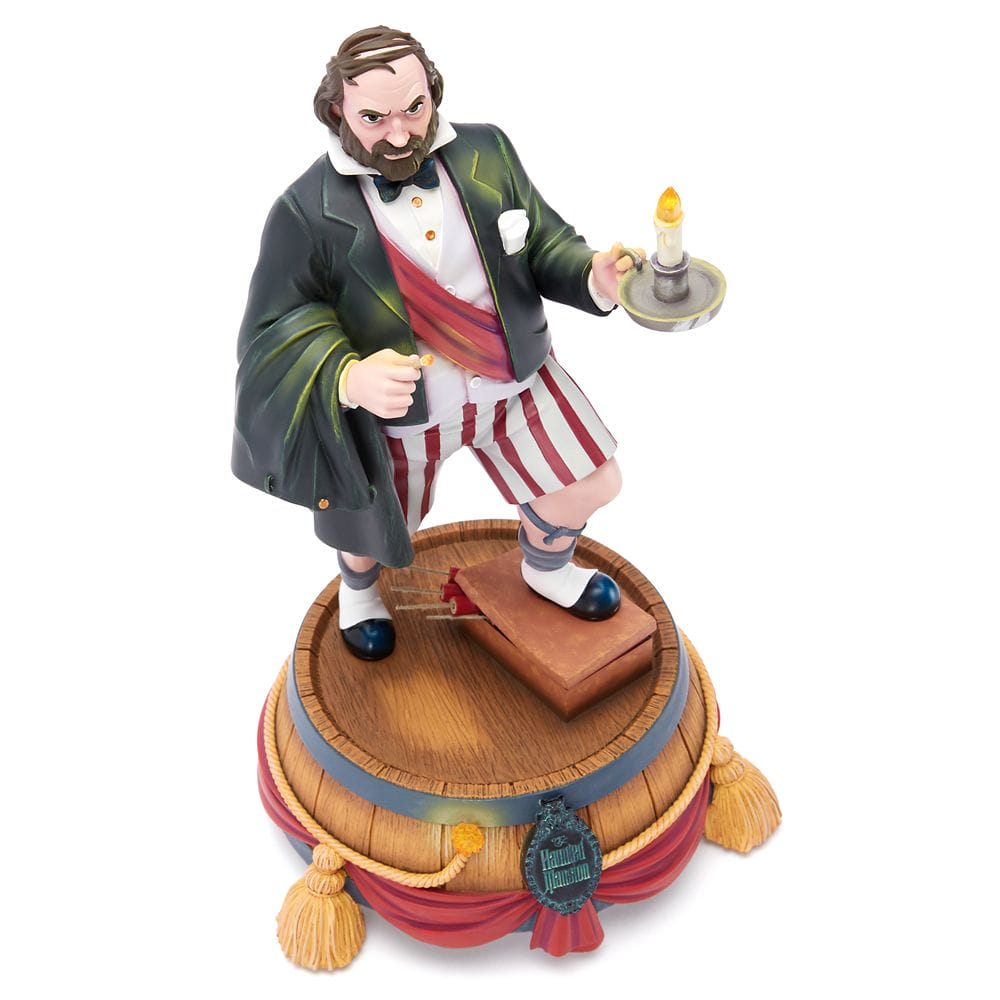 A Haunted Mansion figurine of a man in a jacket, striped shorts, and slippers holding a candle on a decorated base.