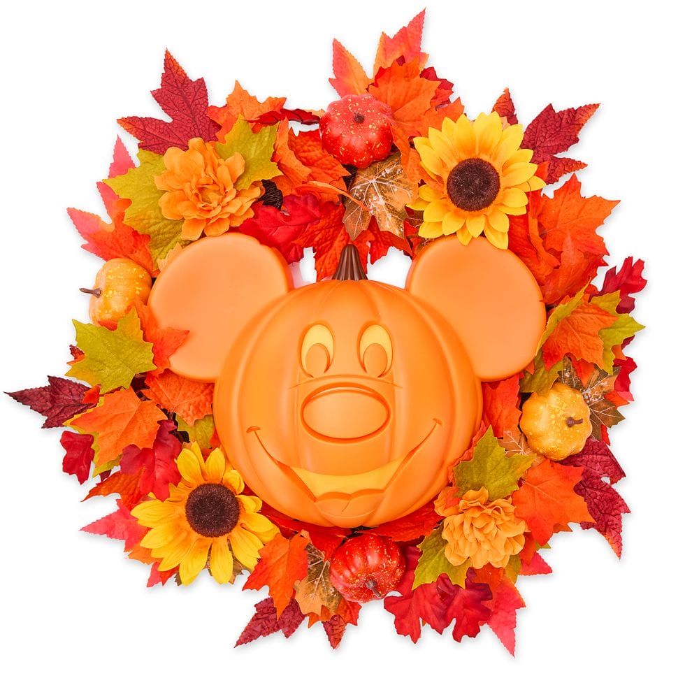 Mickey Mouse pumpkin surrounded by autumn leaves, sunflowers, and small gourds on a white background.