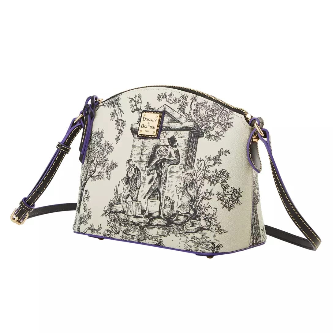 A cream-colored crossbody bag from the Haunted Mansion Collection with black toile print and gold Dooney & Bourke logo plate.