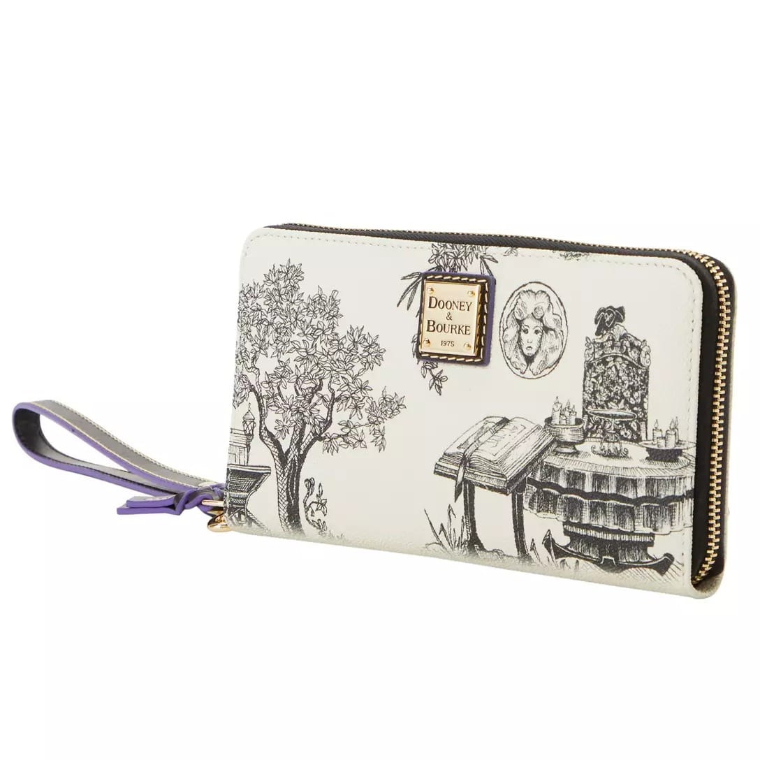 White wristlet wallet with black line art of trees and books, gold zipper, and a Disney Store Dooney & Bourke logo patch.