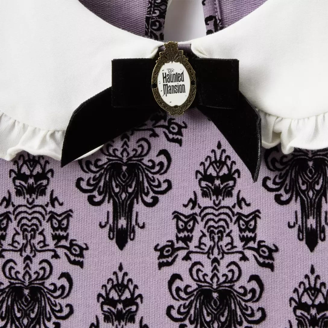 Close-up of a purple and black patterned dress with white collar, black bow, and Disney Store Haunted Mansion pin.