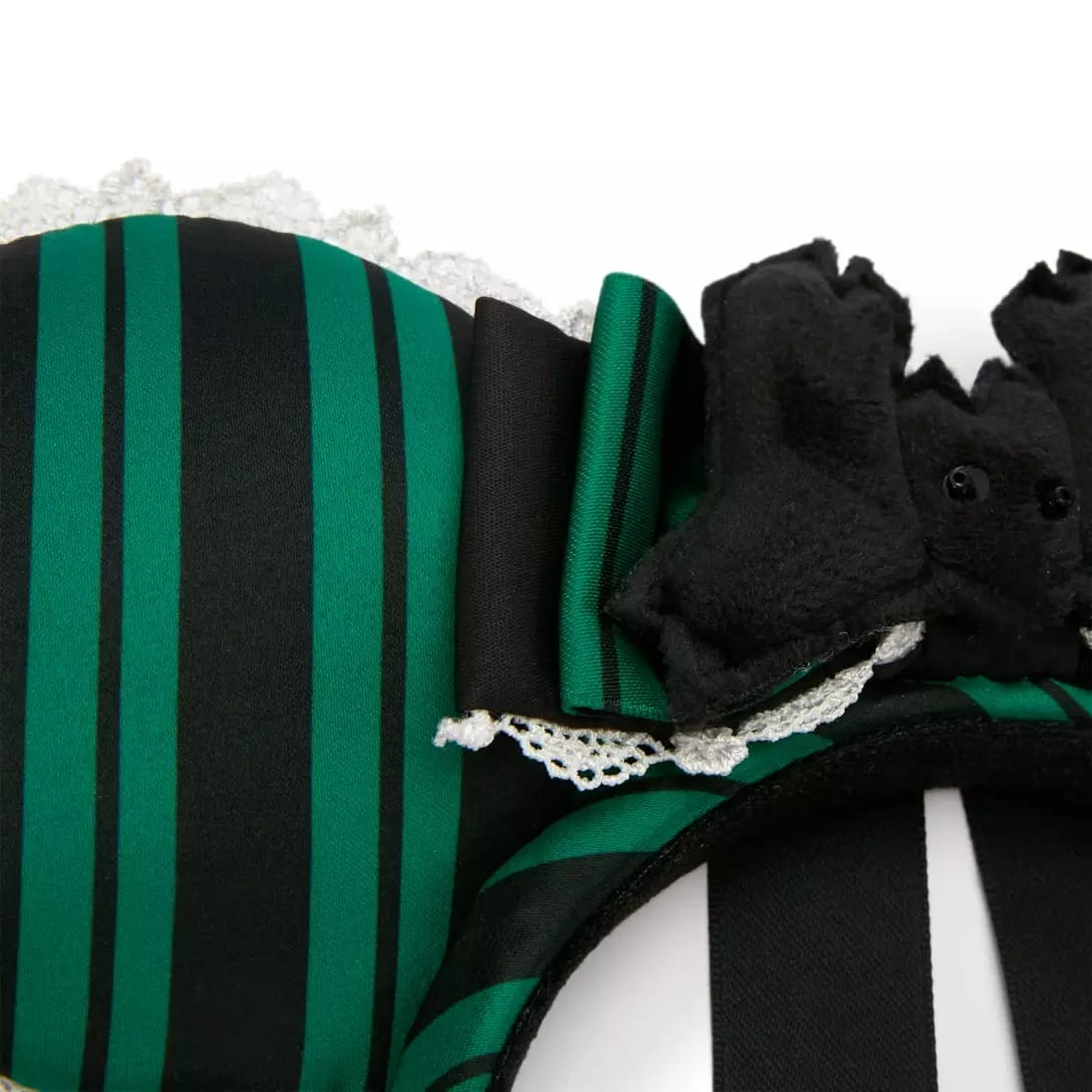 Close-up of a green and black striped headband with lace, a bow, bat ears, and Haunted Mansion flair.