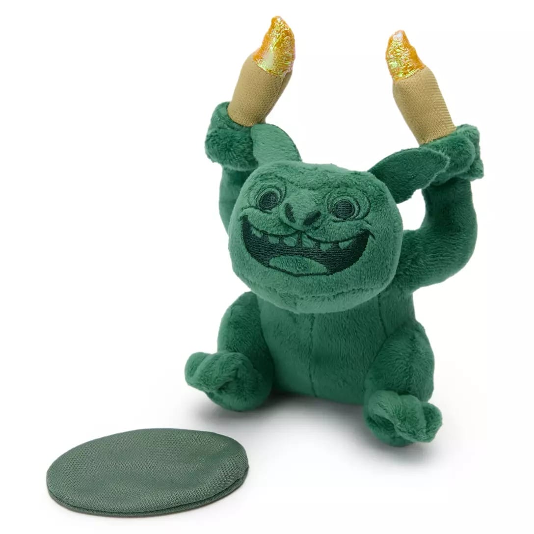 Green plush monster from the Haunted Mansion Collection sits with raised candle arms beside a round green mat. Disney Store exclusive.