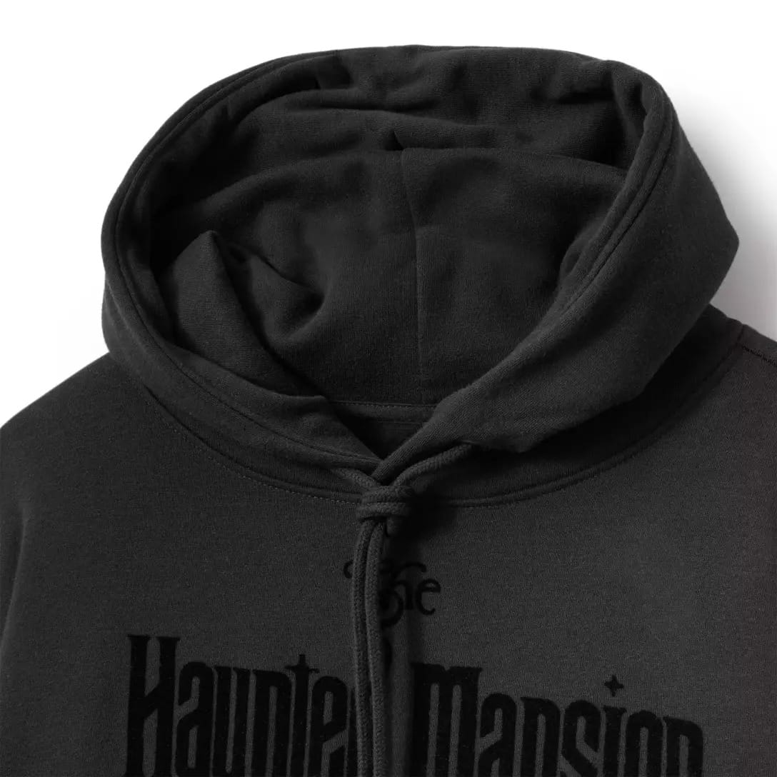 Close-up of a black hoodie from the Haunted Mansion Collection with a drawstring hood and partial chest text.