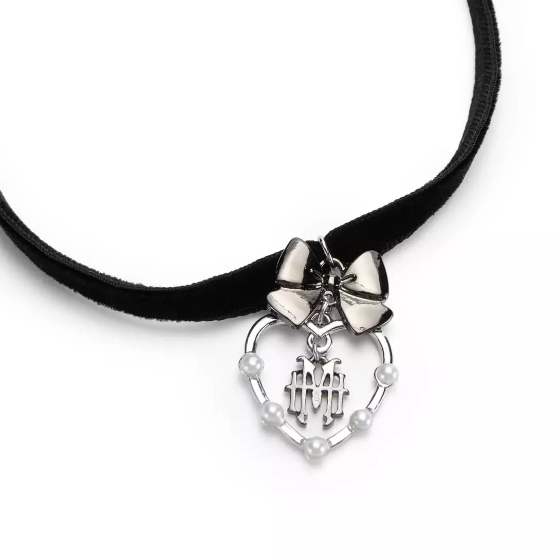 Black velvet choker from the Haunted Mansion Collection with a silver bow and a heart-shaped pendant adorned with pearls and “MH.”