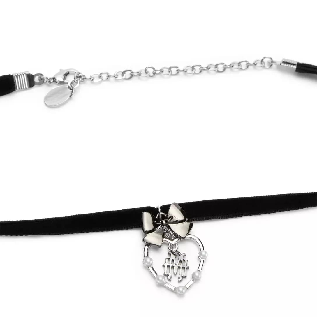 Black velvet choker from the Haunted Mansion Collection with silver chain, bow, and a heart-shaped skeleton hand pendant.