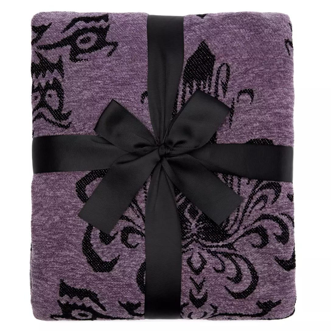 Folded purple blanket with black floral pattern from the Haunted Mansion Collection, tied with a black ribbon in a bow.