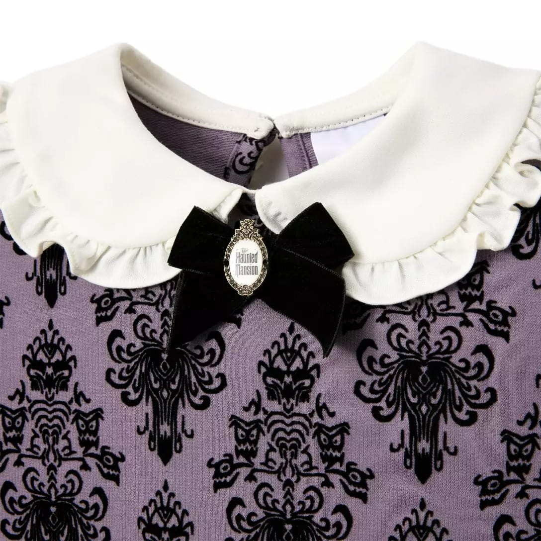 Close-up of a dress with a white ruffled collar, black bow, and "Haunted Mansion" cameo from the Disney Store.