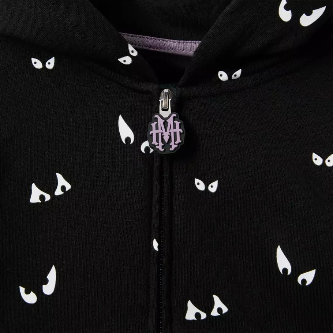 Close-up of a black hoodie from the Haunted Mansion Collection, with cartoon eyes and "HM" zipper pull.