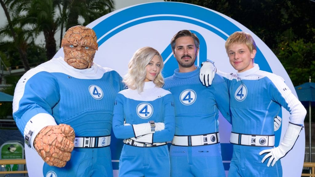 Four people in Fantastic Four costumes pose by a huge logo at Disneyland Park.