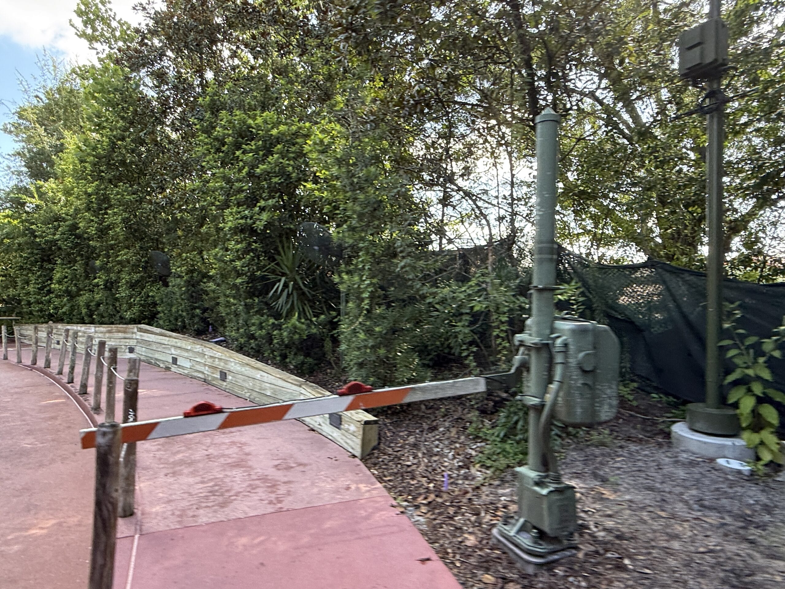A barrier blocks a red walkway near dense greenery by Frontierland Station on the Walt Disney World Railroad.