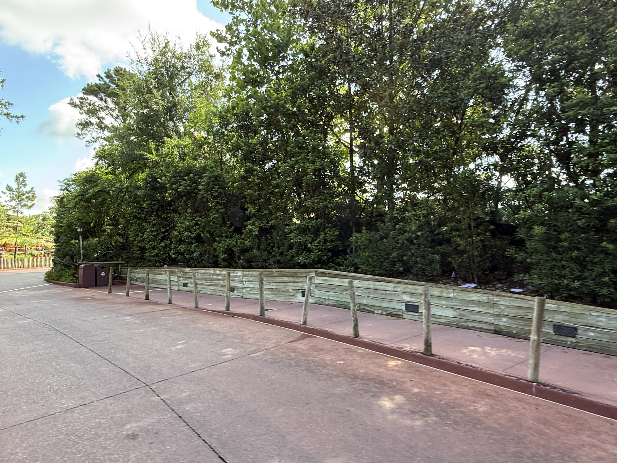 A paved walkway curves by a wooden fence near the closed Frontierland Station of the Walt Disney World Railroad.