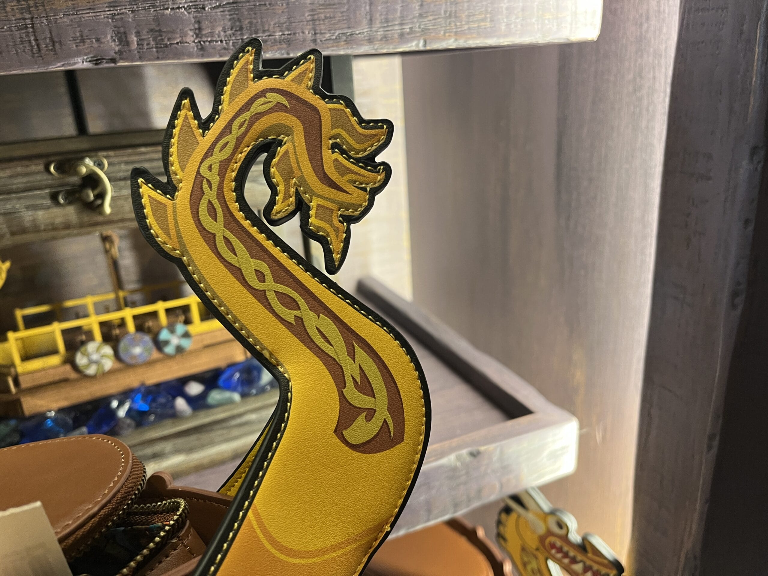 Close-up of a yellow and orange dragon-shaped item on display at Hiccup's Work Shop, with shelves in the background.