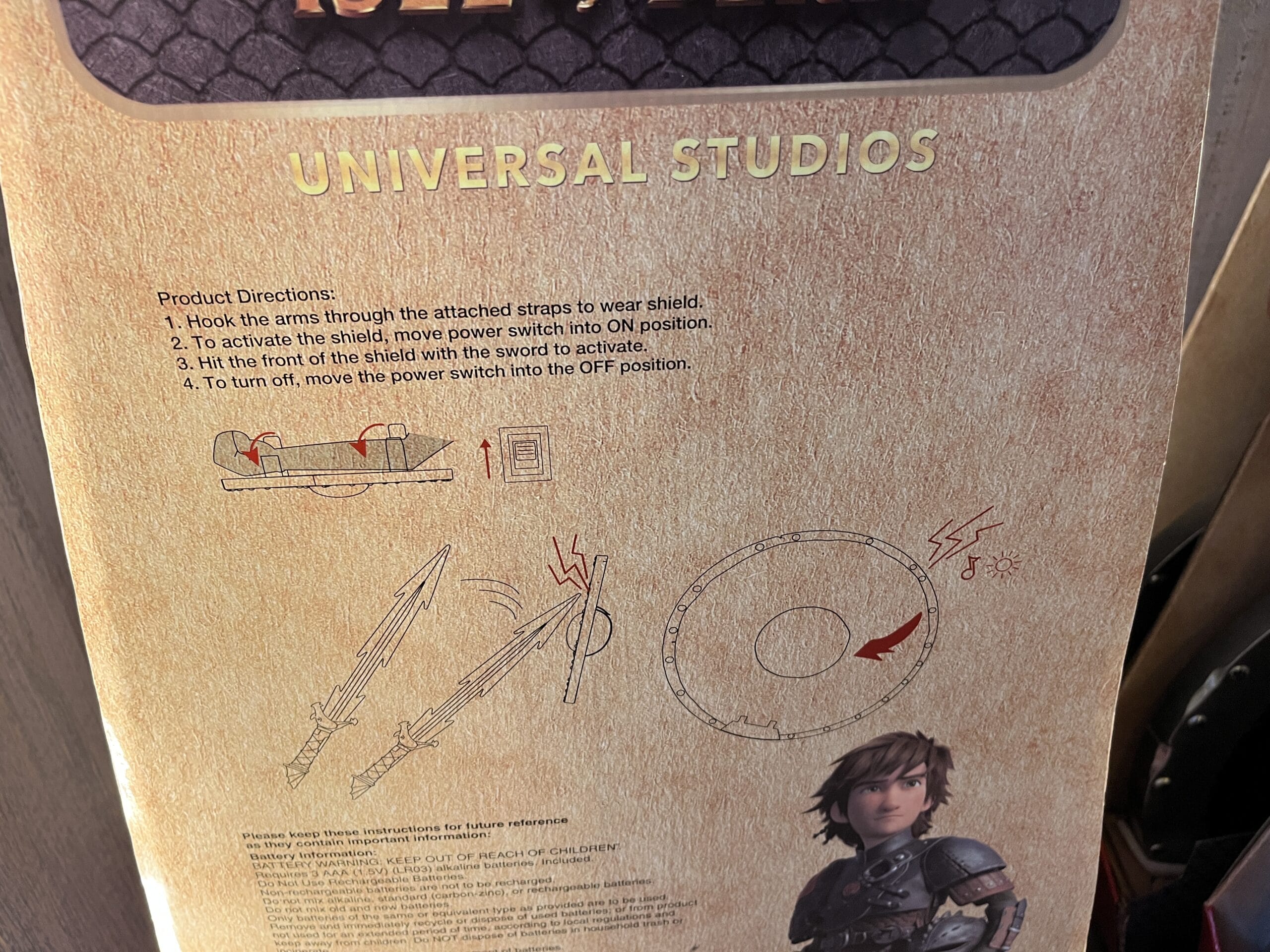 Product directions for a How to Train Your Dragon toy shield from Hiccup's Work Shop, with illustration at Universal Studios.