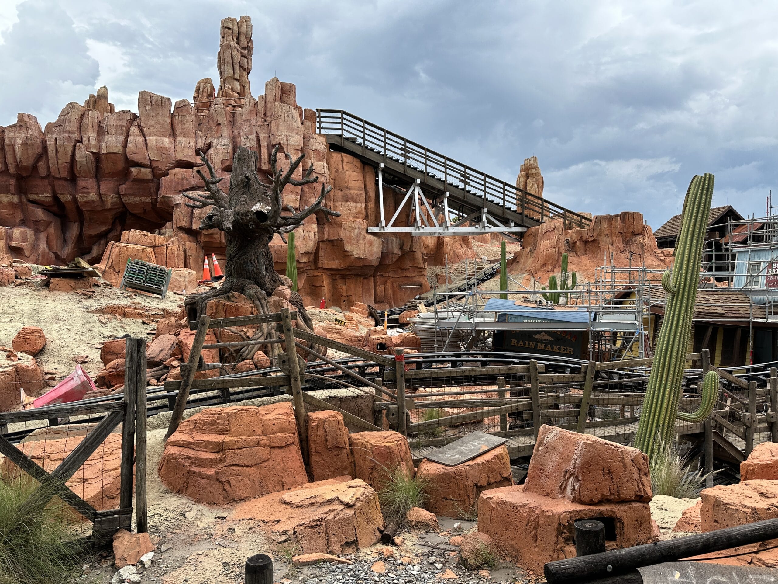 A desert-themed ride with red rocks near the Frontierland Station closure and a spooky tree under a cloudy sky.