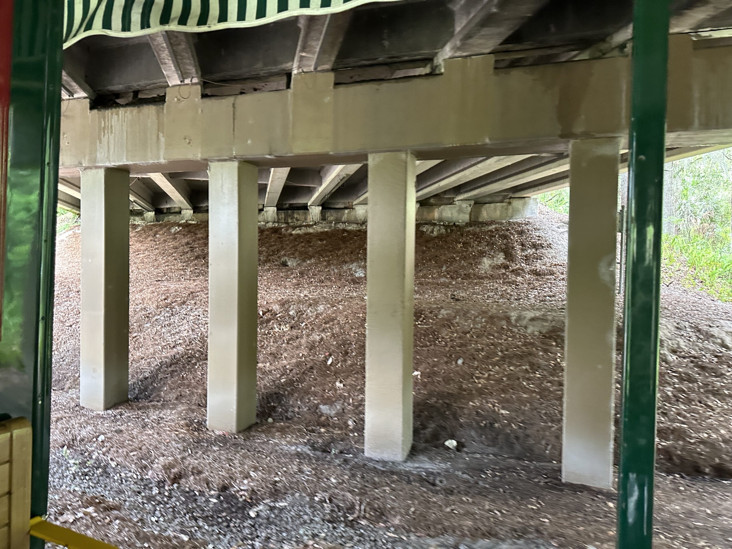 View of concrete bridge supports and dirt piles under the bridge near Frontierland Station on the Walt Disney World Railroad.
