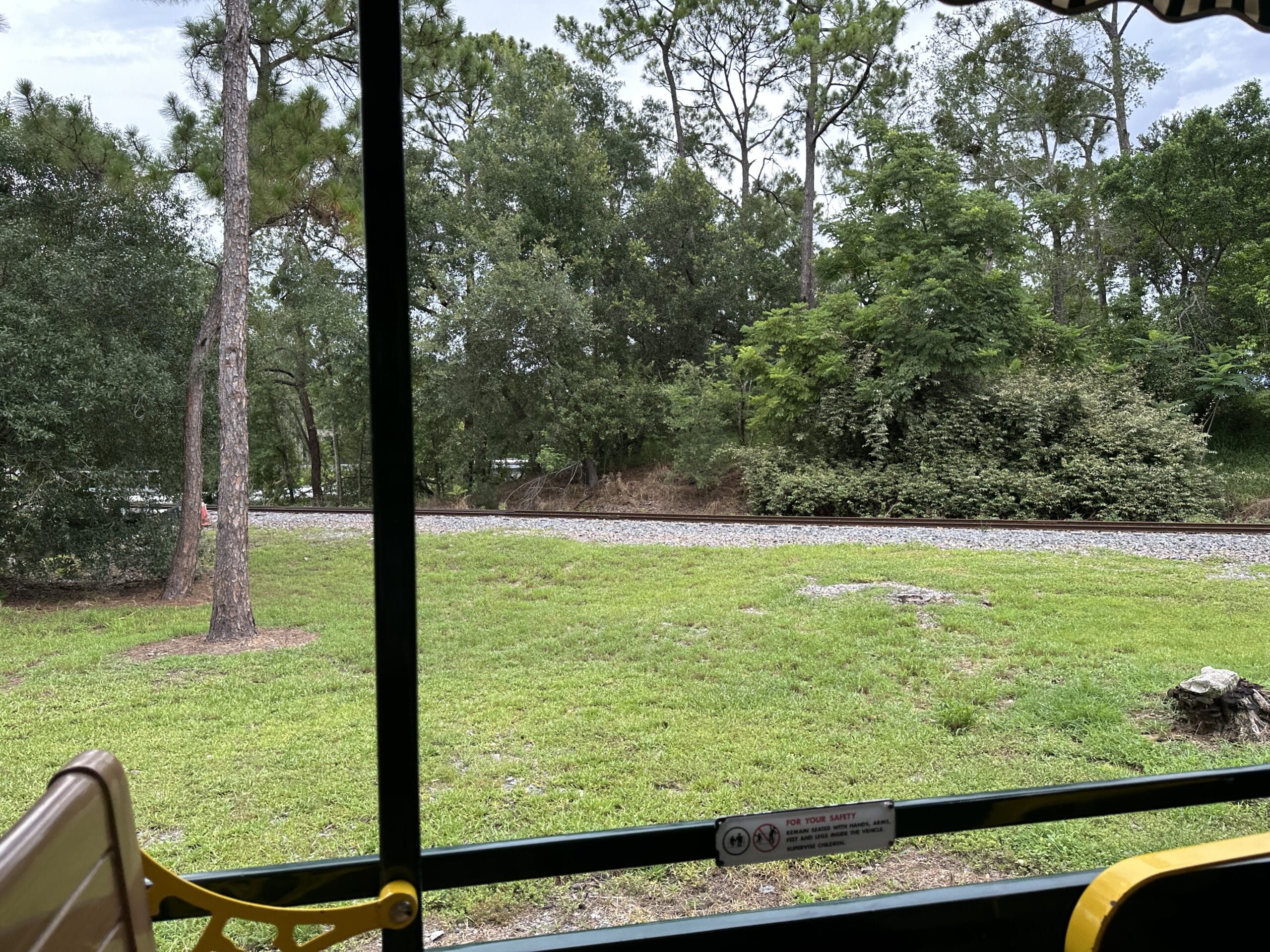 View of train tracks and green trees from a vehicle near the Walt Disney World Railroad’s Frontierland Station closure.