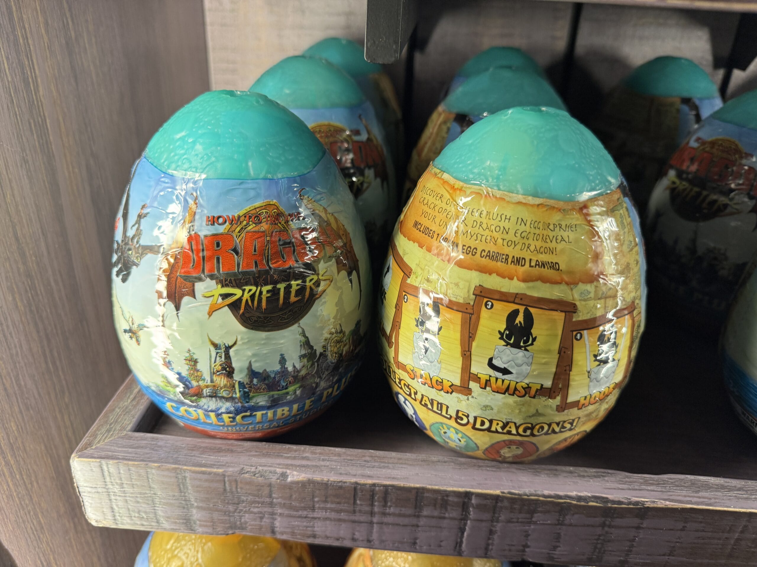 Plastic “How to Train Your Dragon” collectible egg toys from Hiccup’s Work Shop displayed on a wooden store shelf.