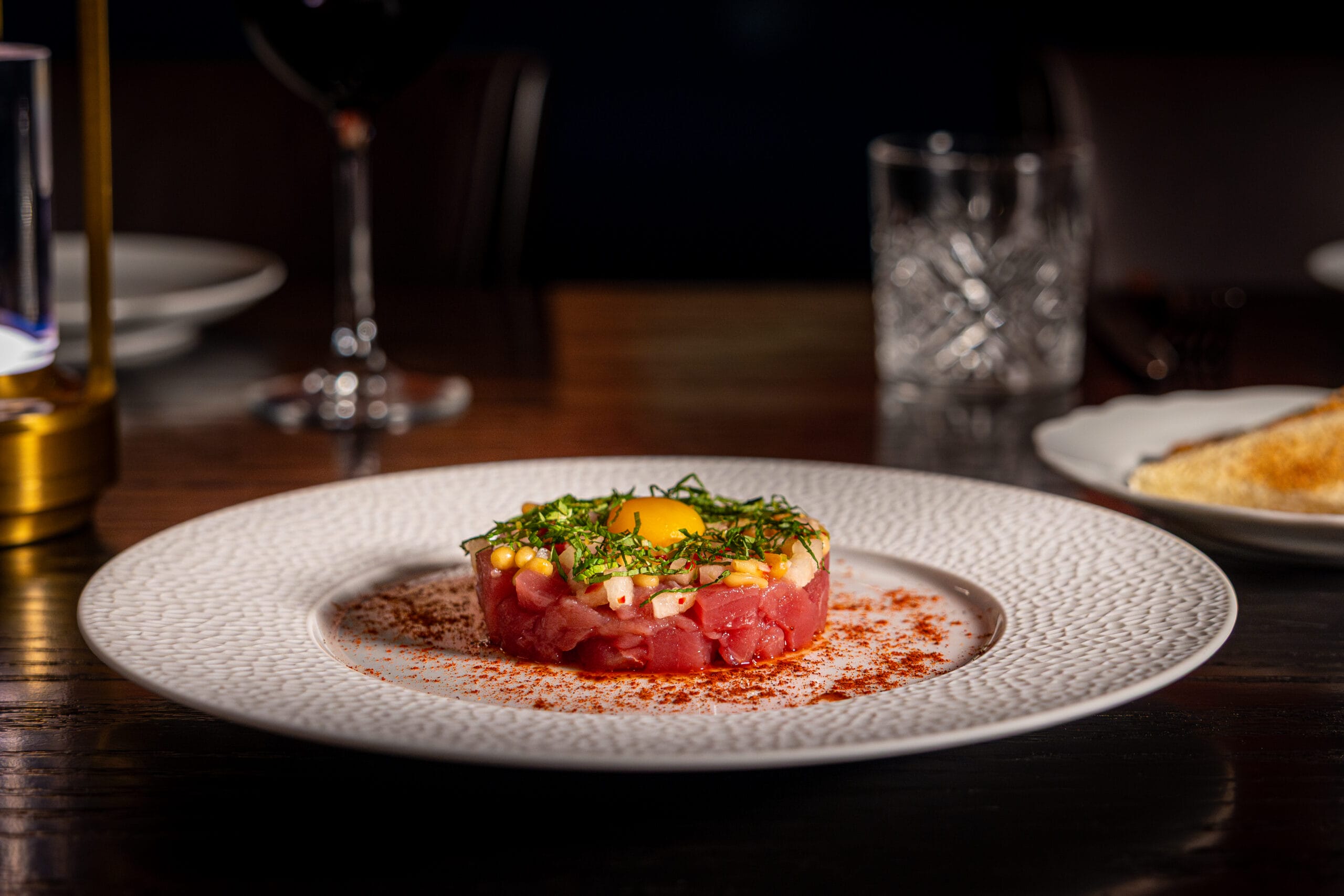 A round steak tartare at Bourbon Steak by Michael Mina, topped with egg yolk, herbs, and paprika at Walt Disney World Dolphin Hotel.