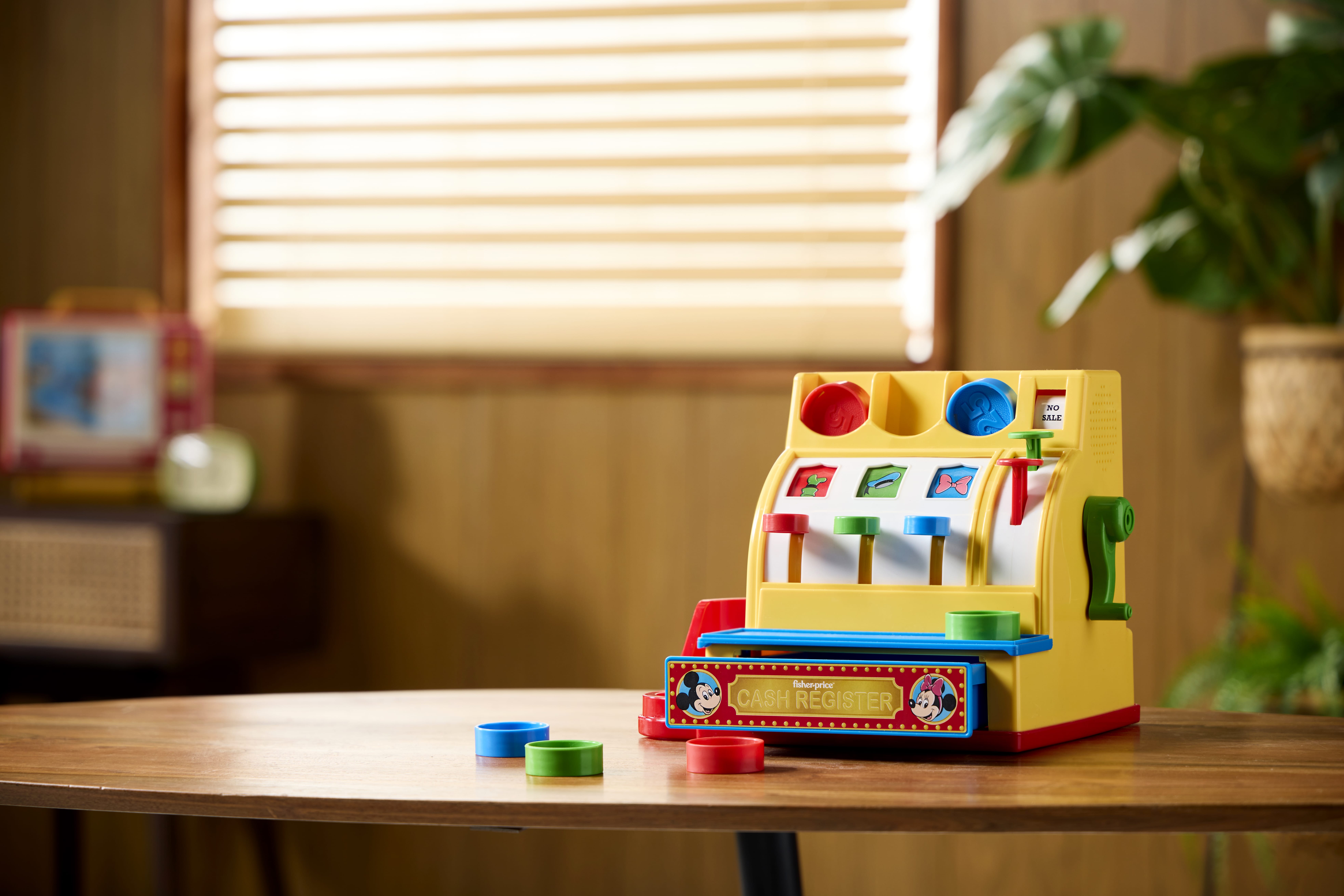 A Retro Fisher Price toy cash register sits on a table, evoking nostalgia. Available Online now.