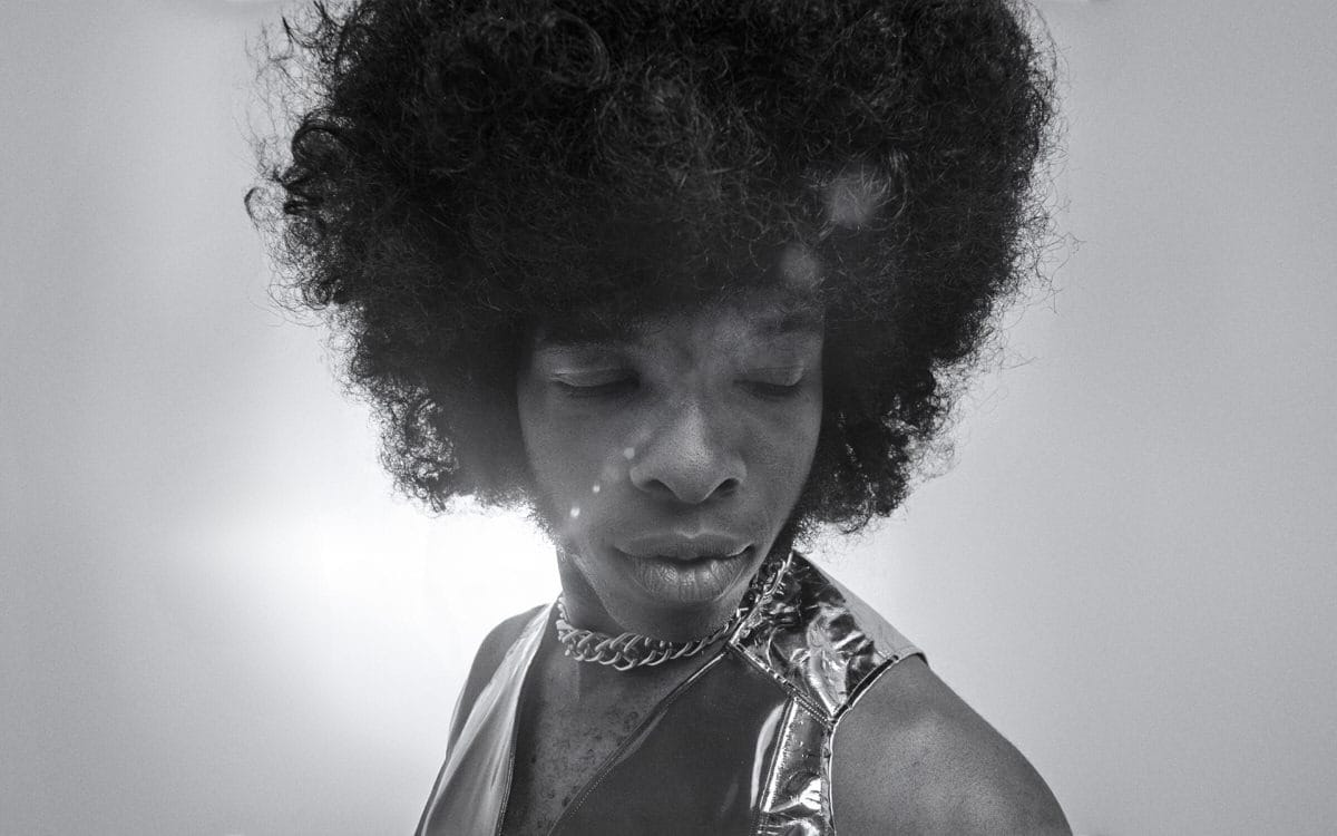 Black and white photo of a person with an afro, metallic top, chain necklace—Emmy Award style shines throughout.