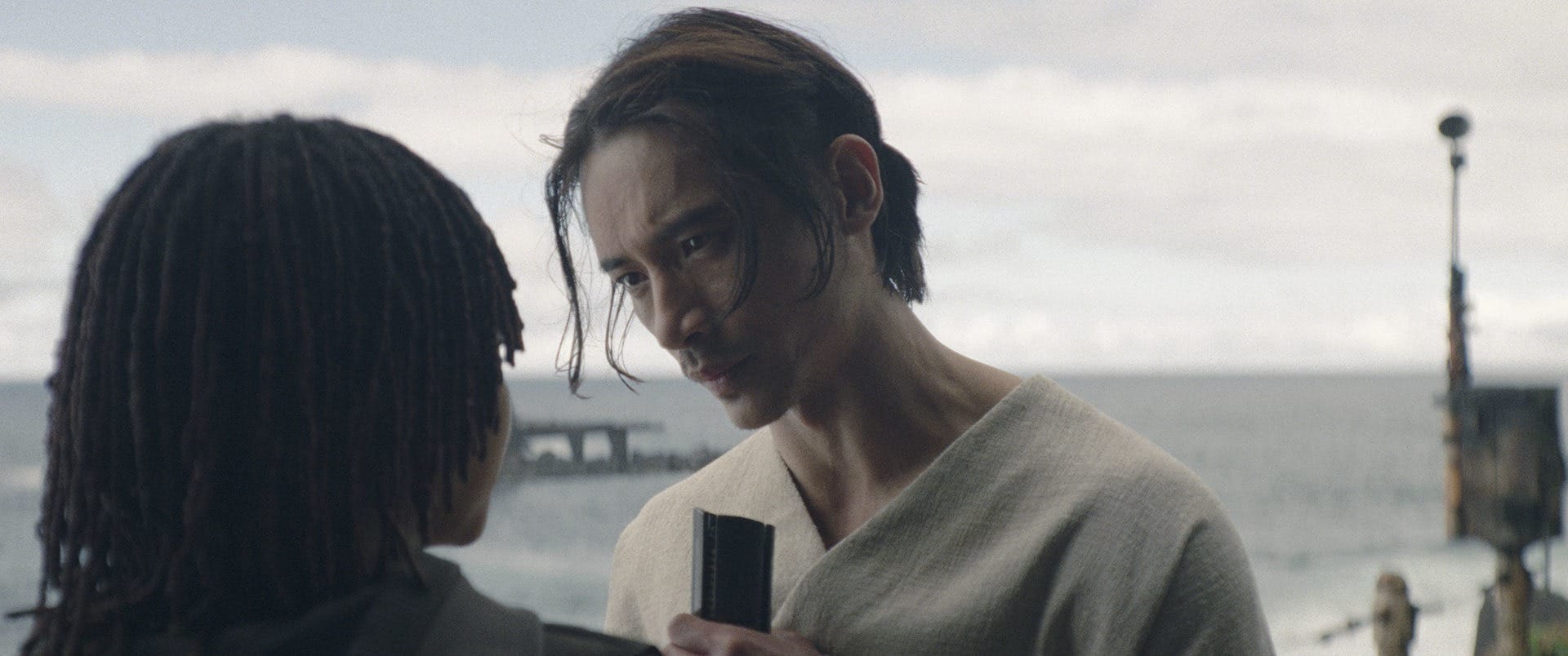 Two people stand close by the ocean, one with an intense expression, reminiscent of an Emmy Awards scene.