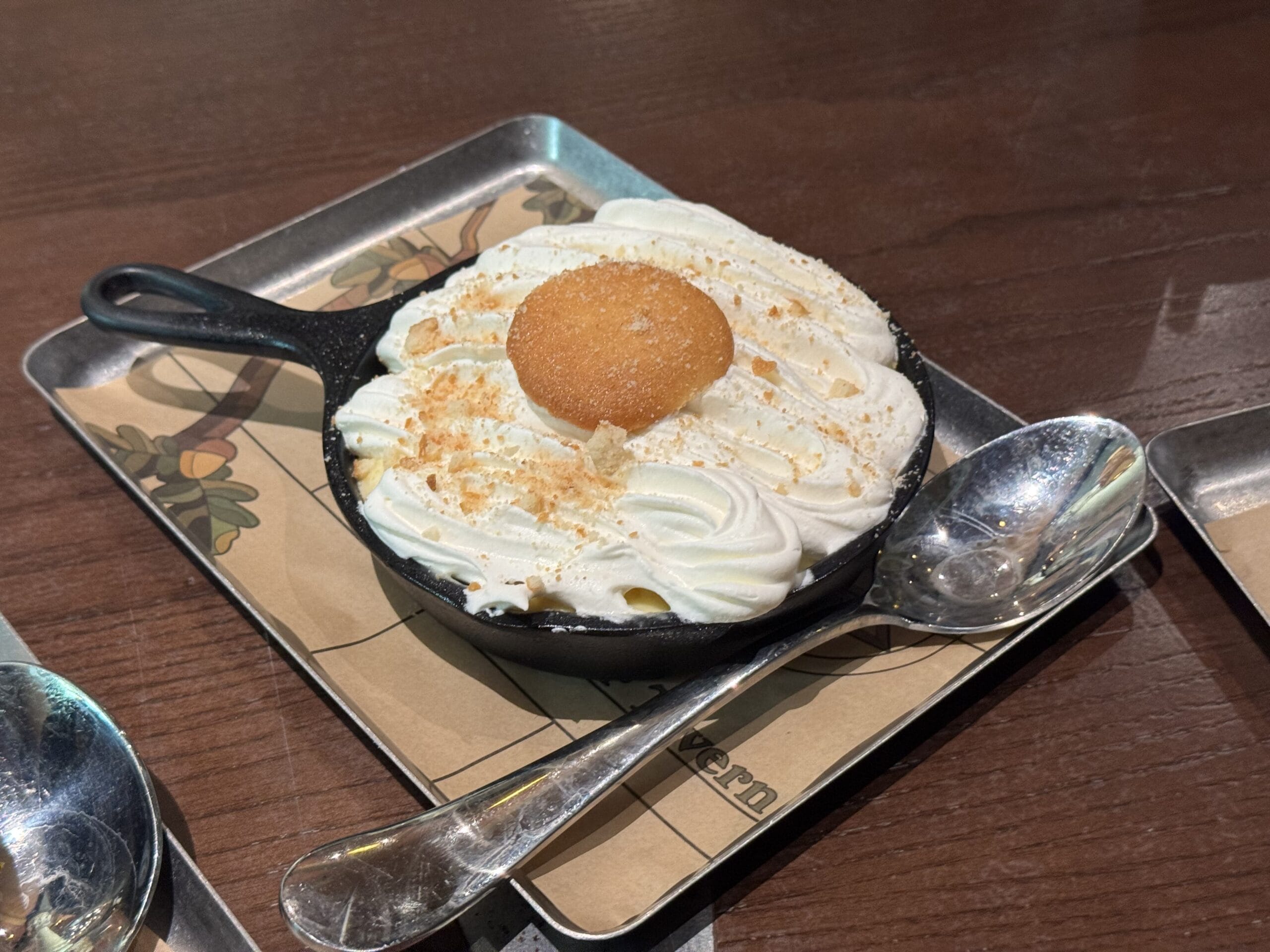 A skillet dessert from The Oak & Star Tavern, topped with whipped cream and a round cookie, served on a metal tray.