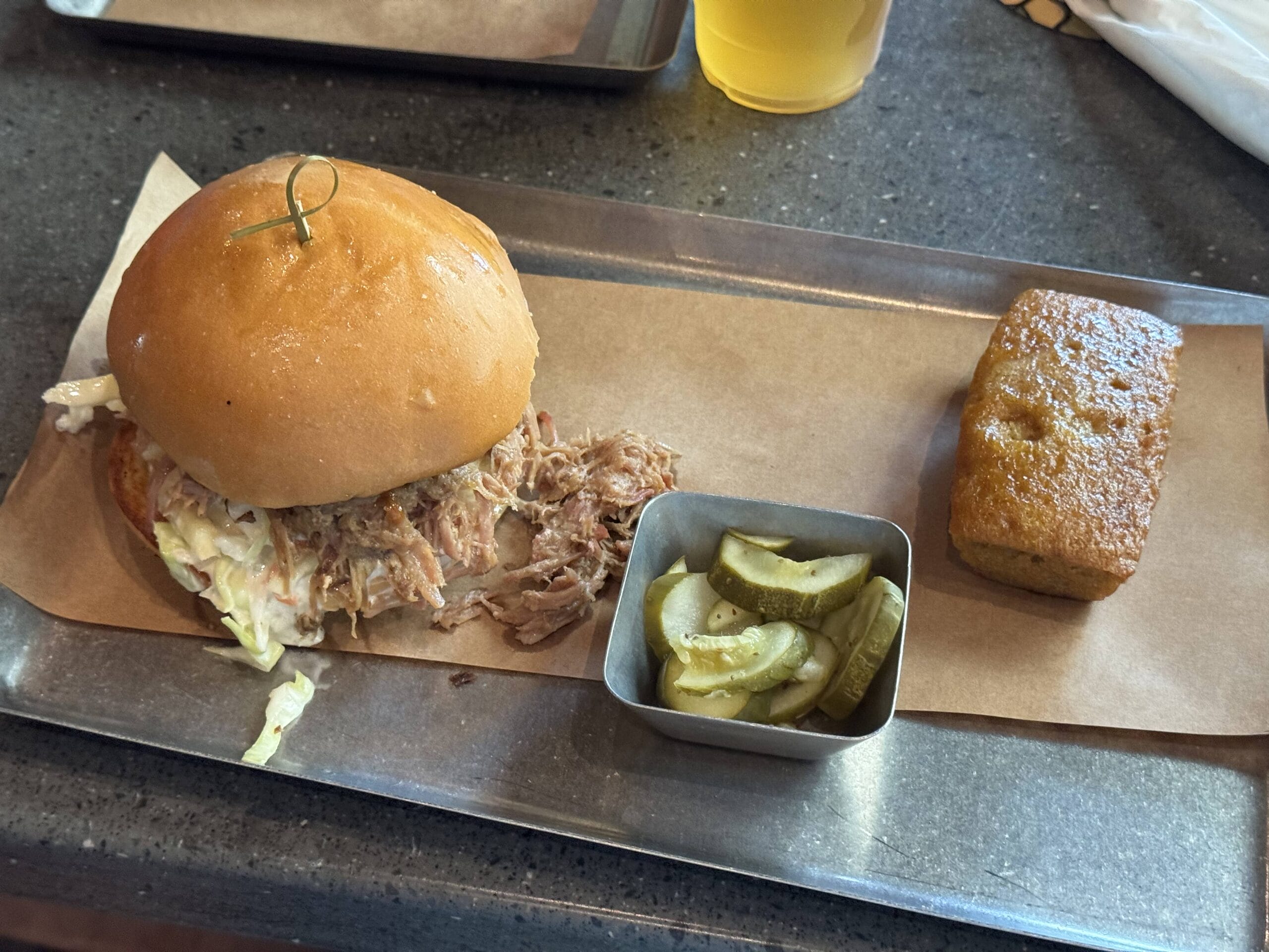 Pulled pork sandwich with coleslaw, pickles, and cornbread—classic fare at The Oak & Star Tavern.
