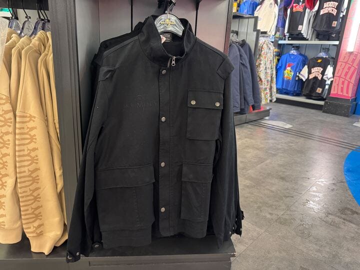 A black jacket from the Mummy Collection with front pockets hangs on display at UNIVRS among colorful apparel.