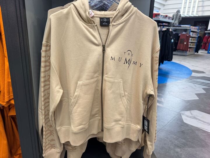 Beige "The Mummy" zip-up hoodie from the UNIVRS Mummy Collection, logo on chest, displayed in-store.