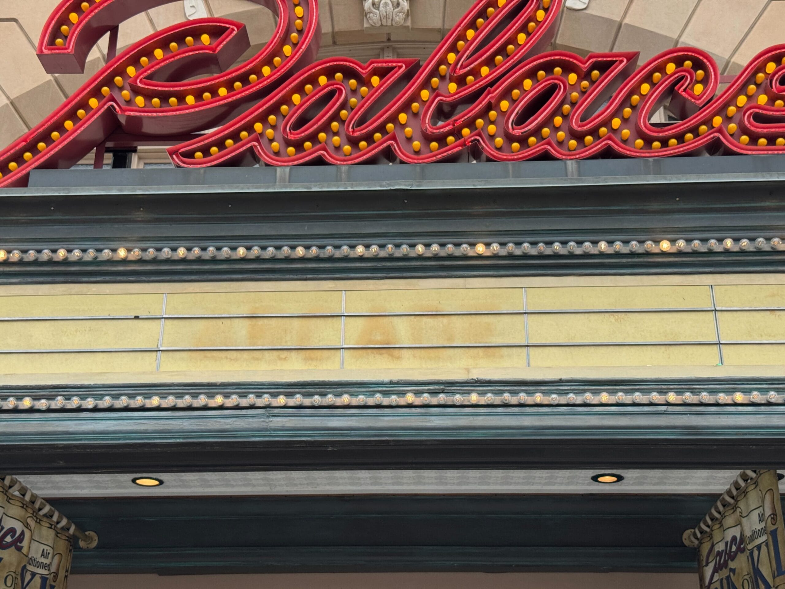 A Palace Theater Arcade marquee with blank spaces glows beneath the iconic red sign above it.