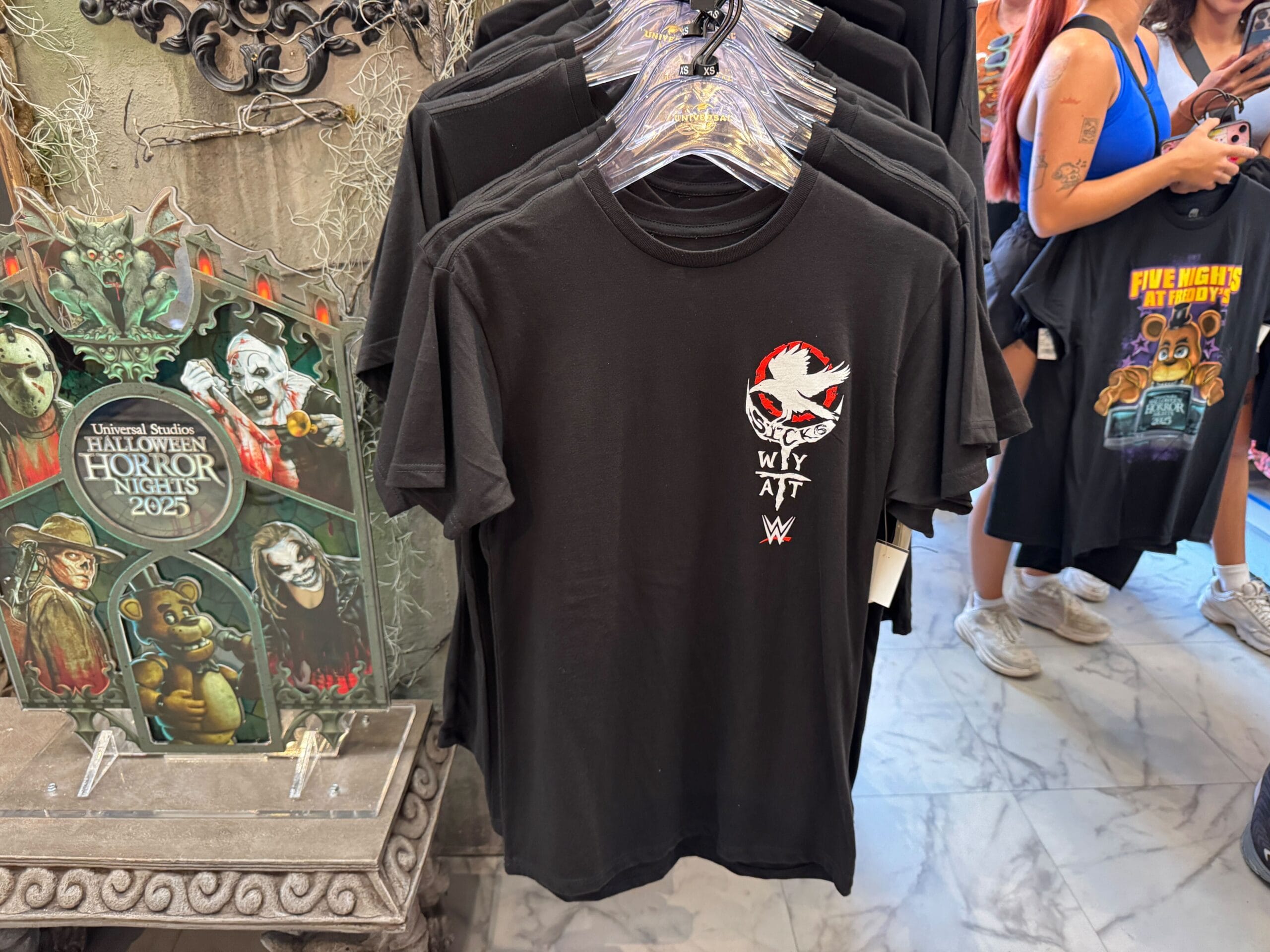 Black T-shirt with a spooky face design and "Why Att" text, displayed at Universal Studios’ Halloween Horror Nights 2023.