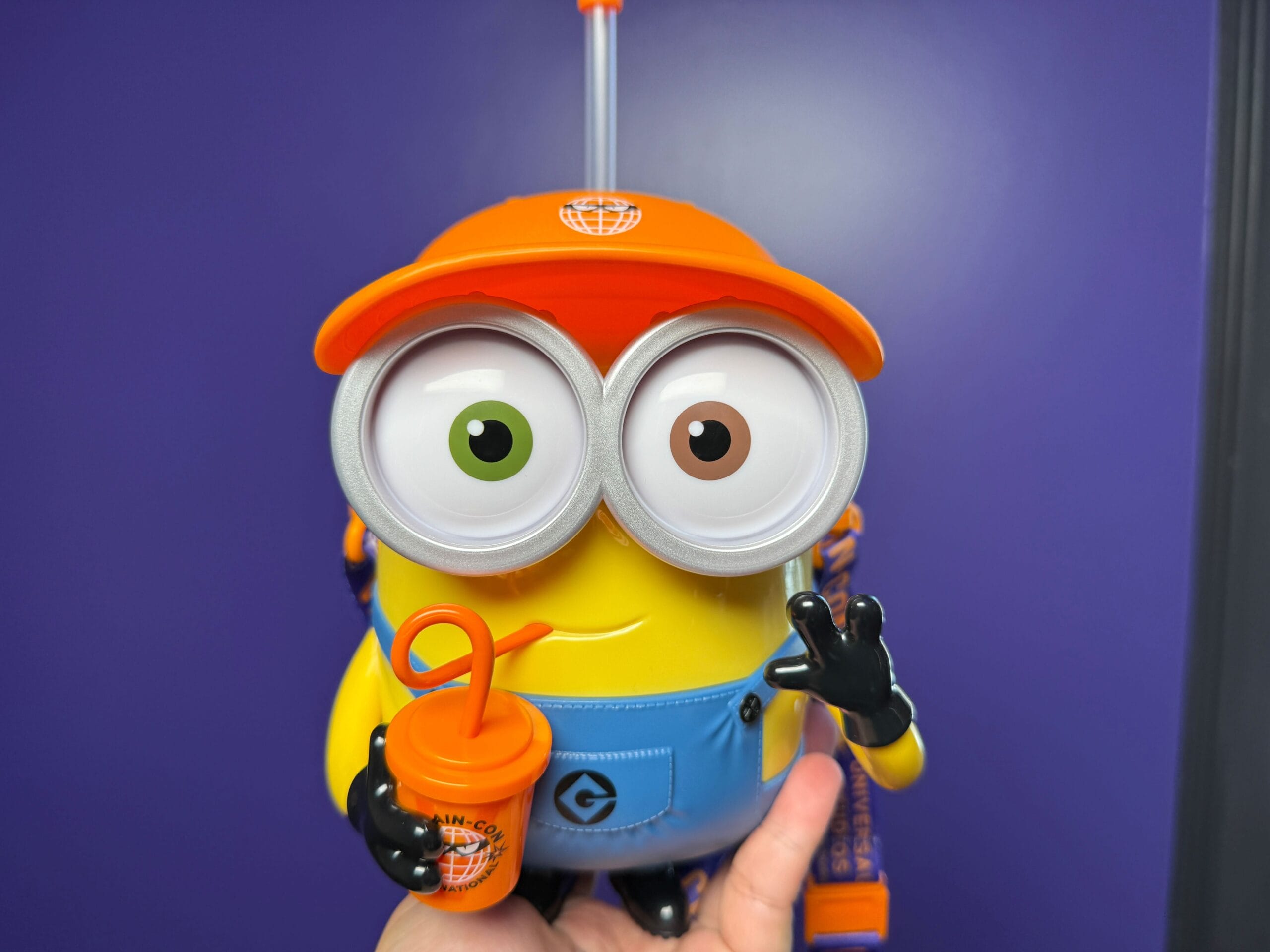A Minion Popcorn Bucket toy from Universal Studios Japan, in an orange cap with a drink cup and mismatched eyes.
