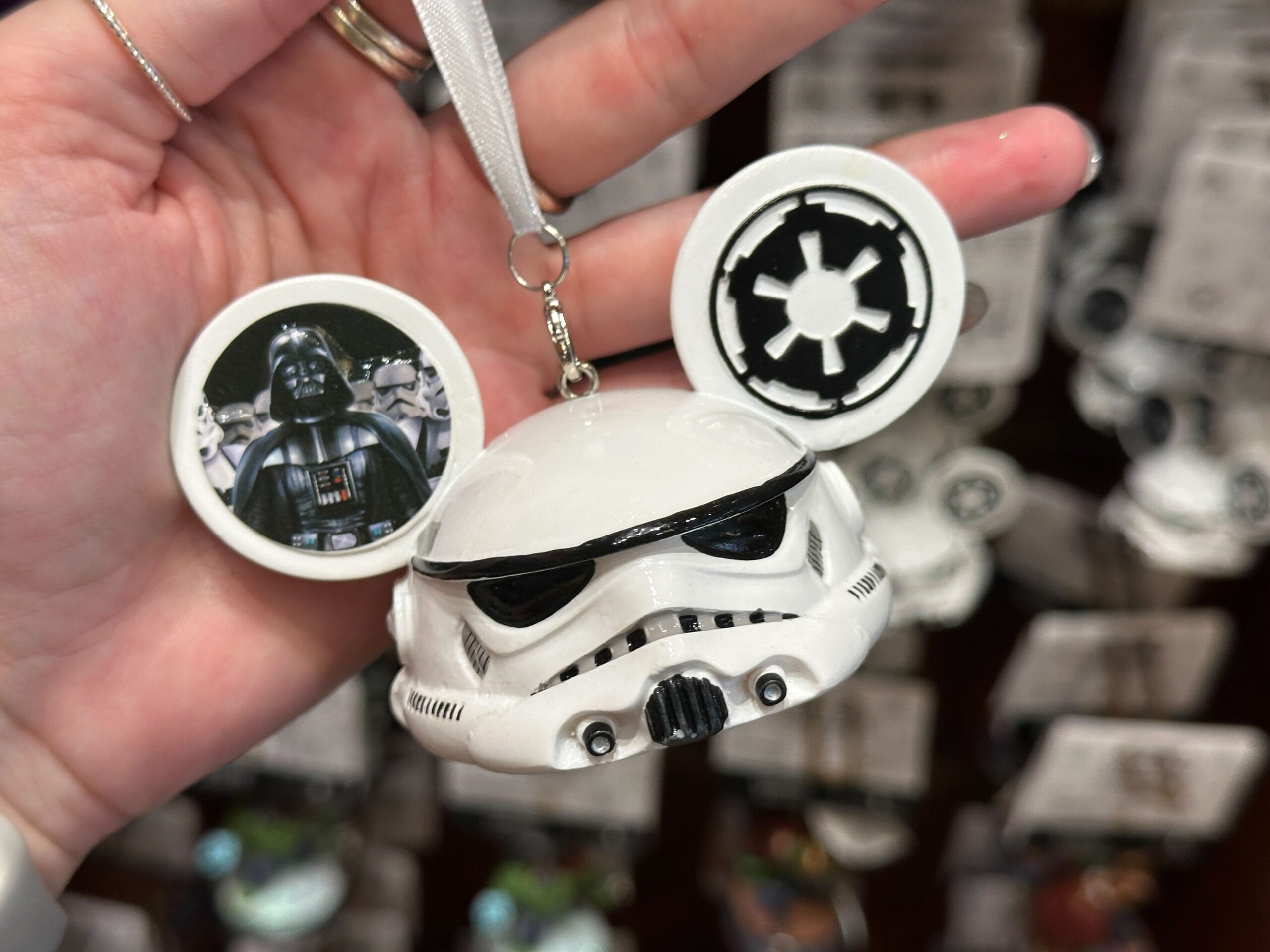 Hand holding a Stormtrooper Mickey Mouse ornament with Darth Vader and Empire logo on the ears.