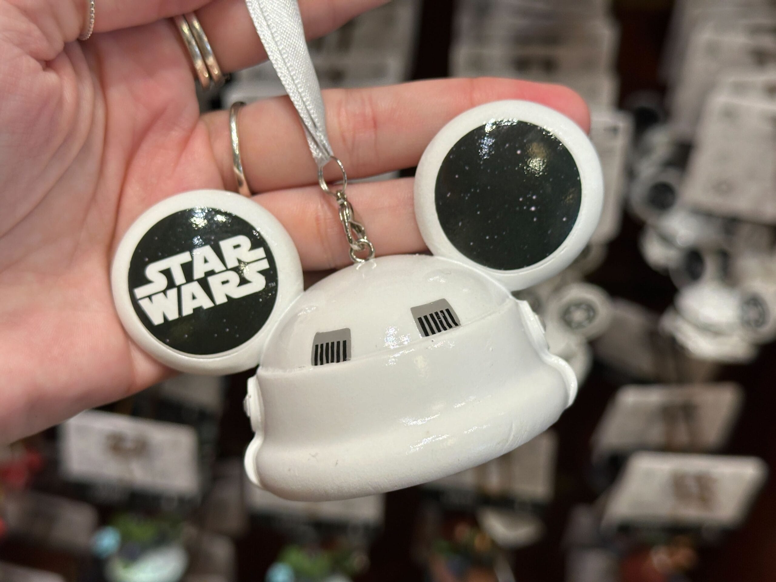 A hand holds a Mickey Mouse ear ornament with "Star Wars" and a stormtrooper helmet design.