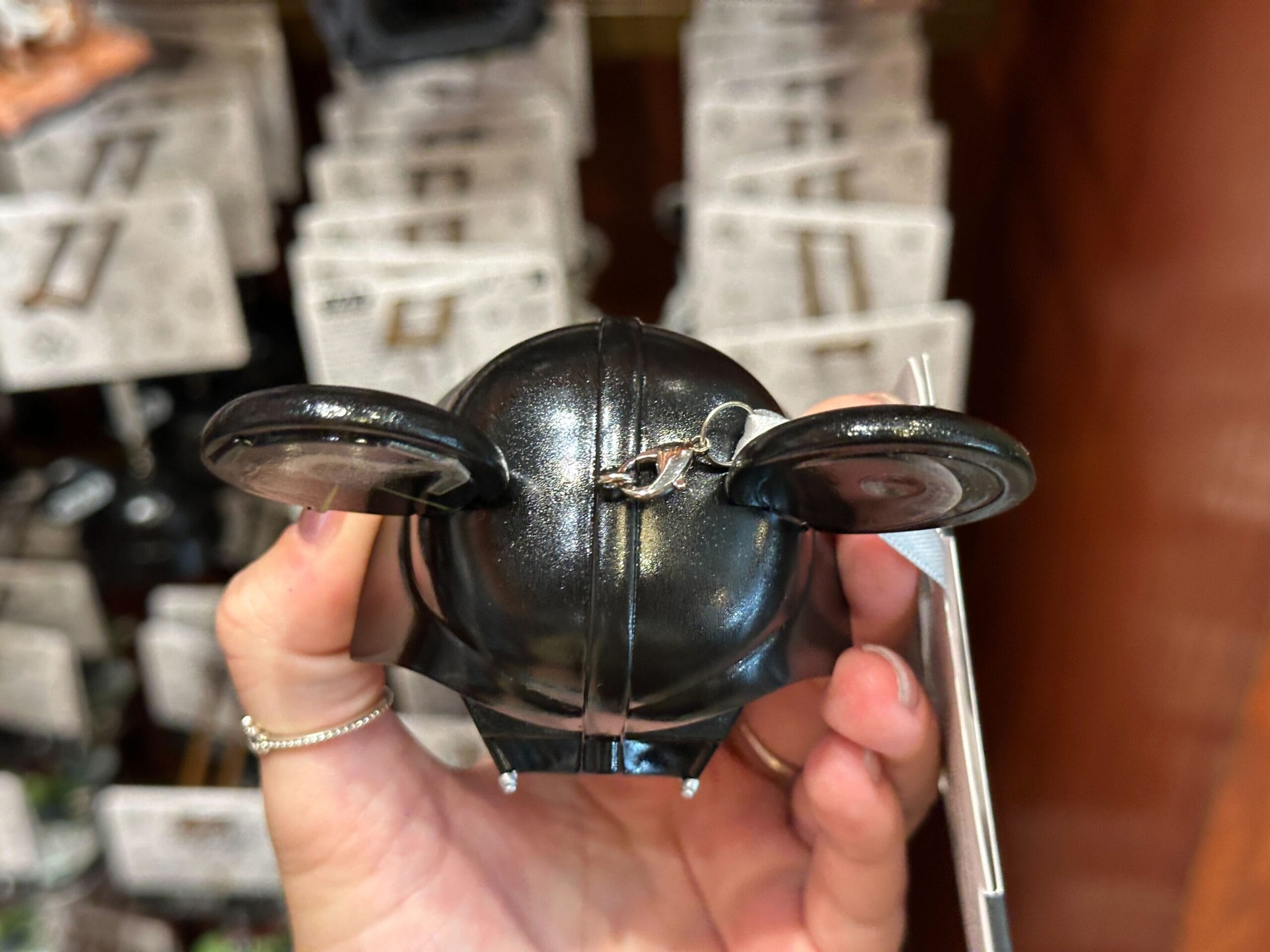 A hand holds a black, mouse-eared keychain with a silver clip attached to the top.