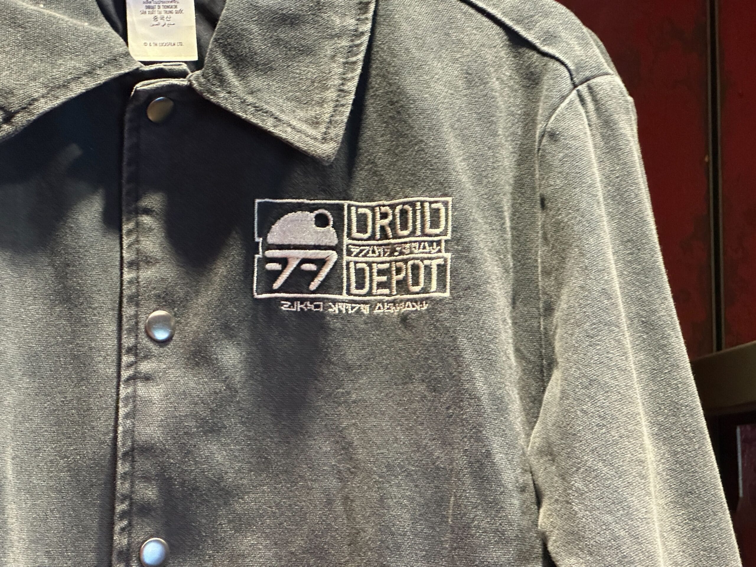 A gray button-up shirt with a "Droid Depot" logo and small Star Wars droid graphic embroidered on the chest.
