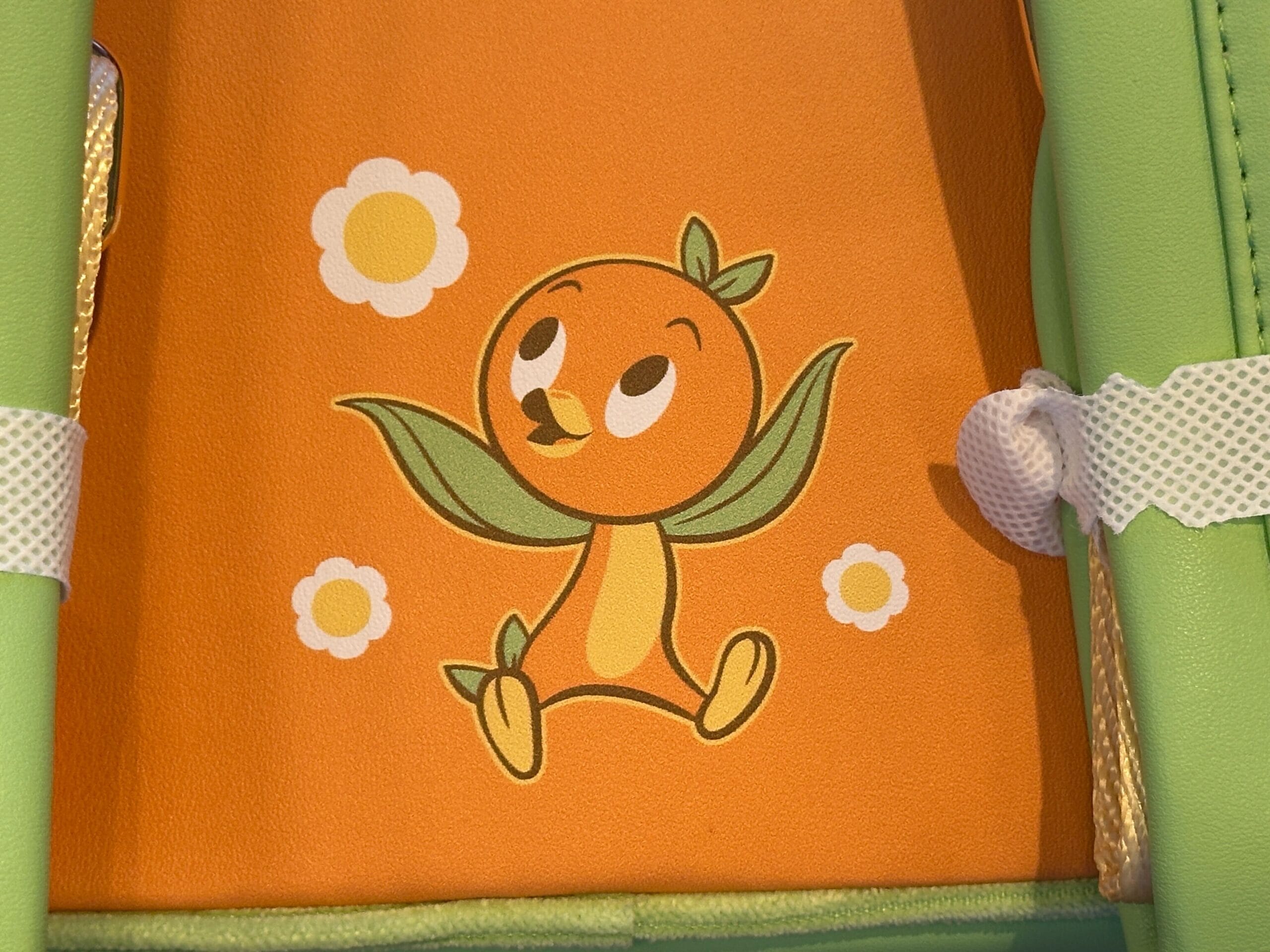 Cartoon Orange Bird character with leaf arms sits among white flowers on a Loungefly-inspired orange and green background.