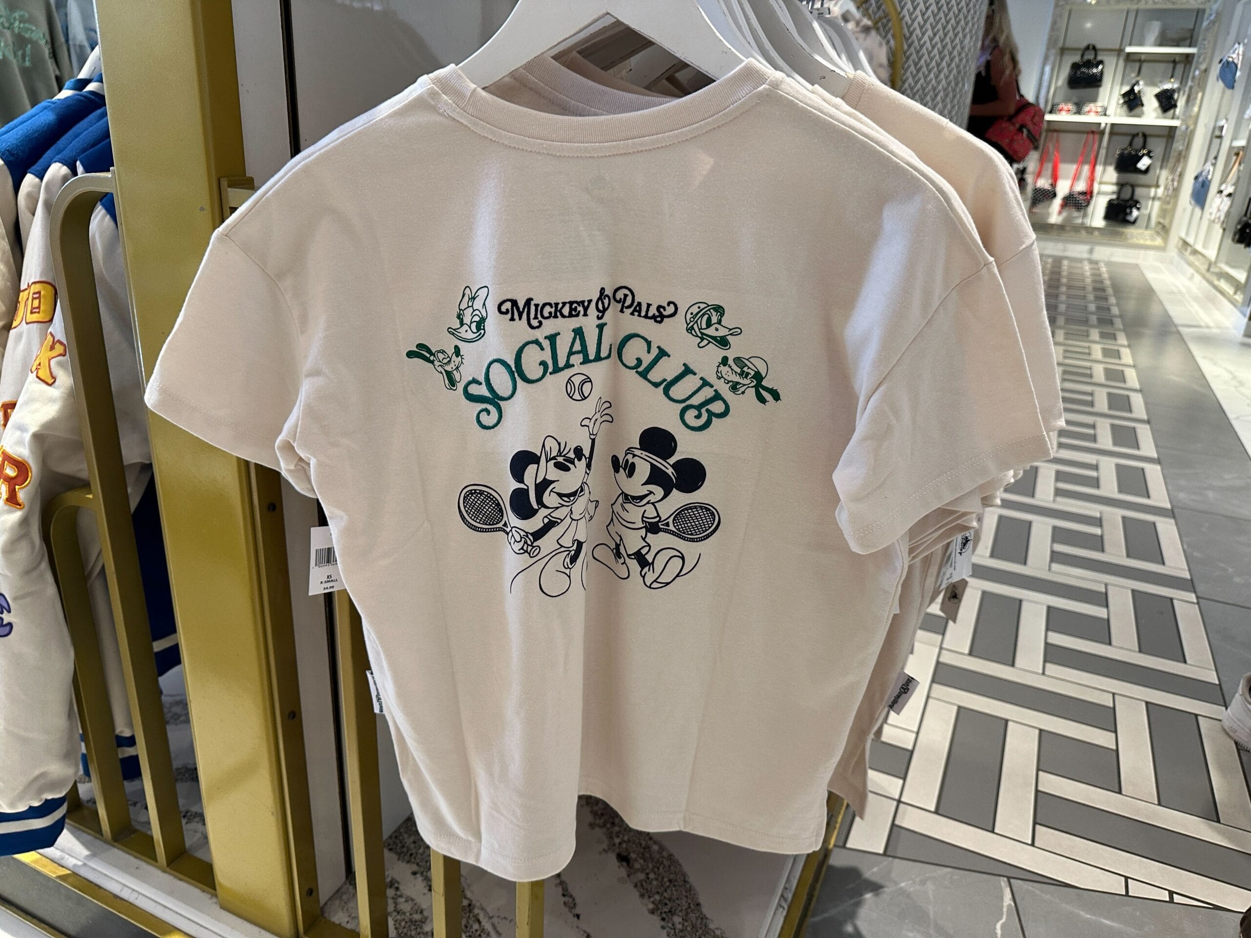 White t-shirt featuring "Mickey & Pals Social Club"—perfect apparel for Walt Disney World and tennis fans alike.